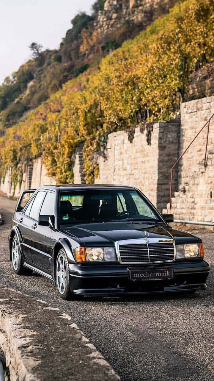 Mercedes 桌布 壁紙 — 一台時尚的黑色賓士190E 2.5-16 Evolution 1停泊在蜿蜒的道路旁，旁邊是梯田式的秋季葡萄園。