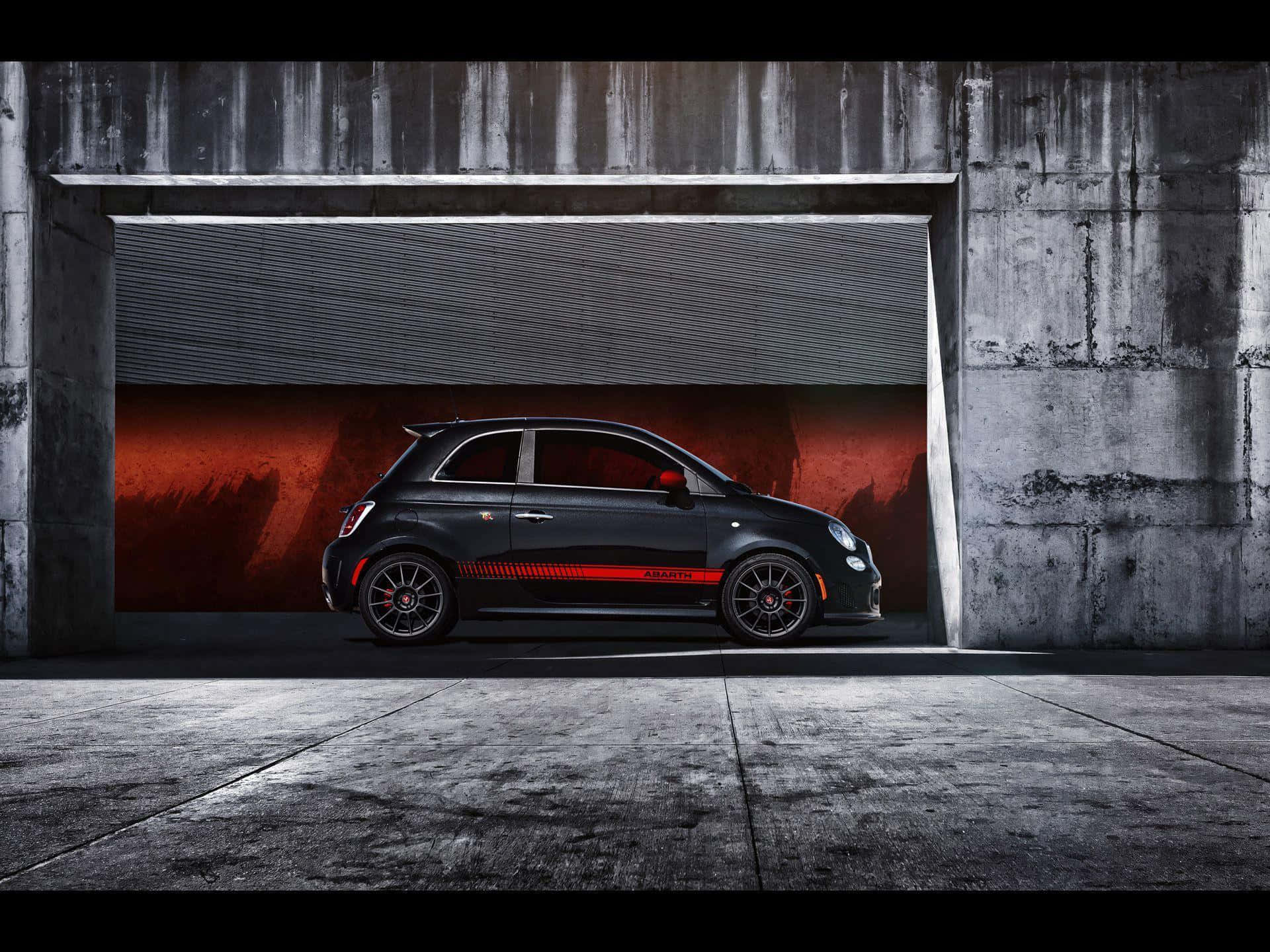 Abarth 桌布 壁紙 — 一台時尚黑色 Fiat Abarth 跑車帶有紅色點綴，停放在一個帶有戲劇性紅色背景的混凝土車庫中。
