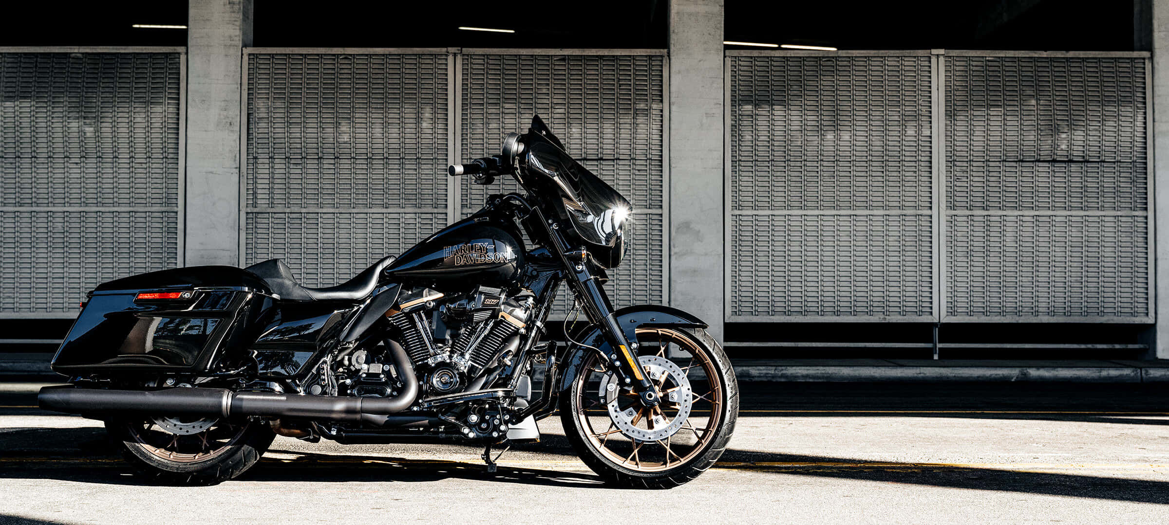 哈雷戴維森 桌布 壁紙 — 一台時尚黑色Harley-Davidson機車停在混凝土高架橋下，背景有工業金屬圍欄。