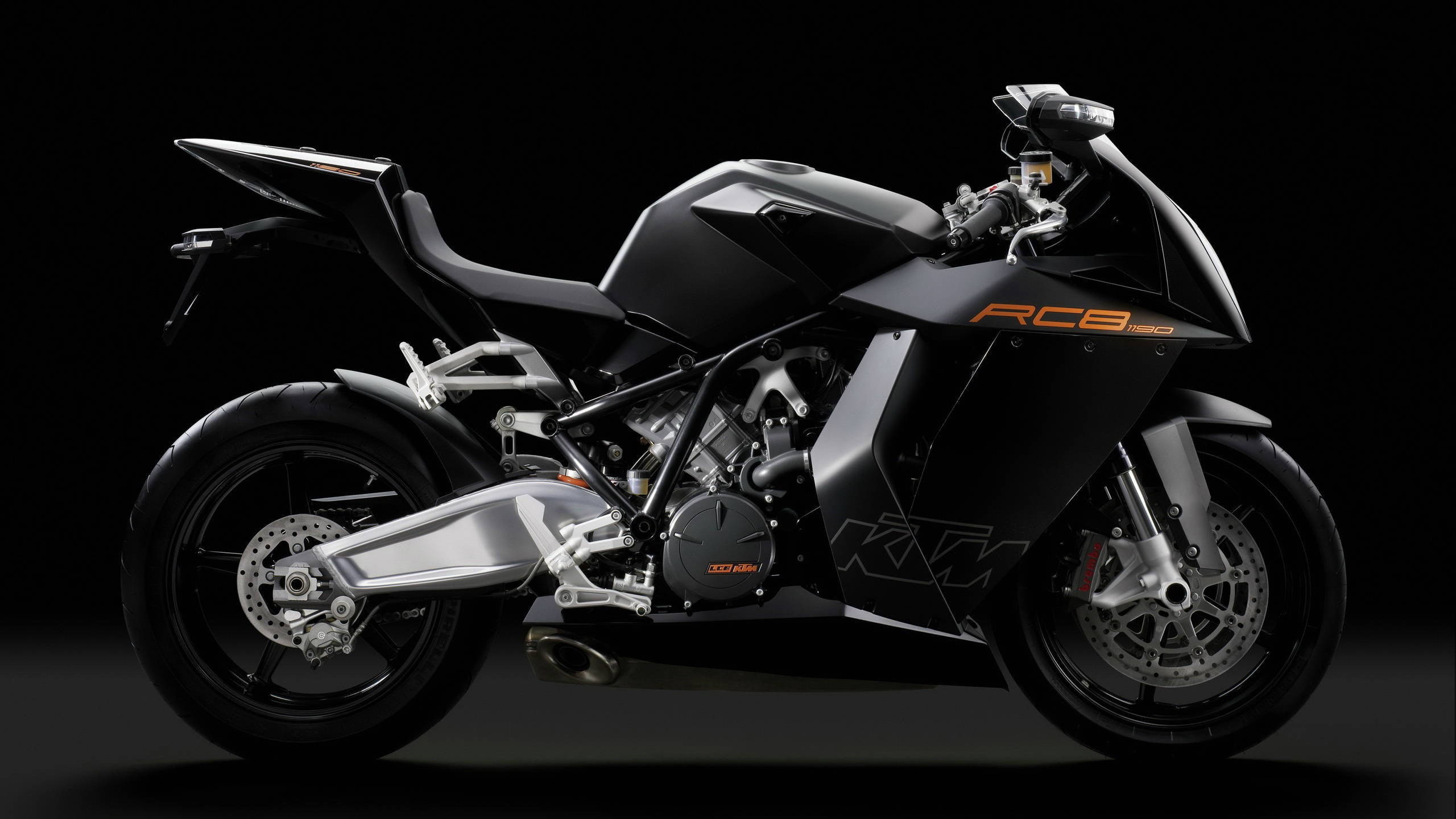KTM 摩托車 桌布 壁紙 — 一台時尚黑色KTM RC8 1190運動機車，帶有橙色點綴，在深色攝影棚背景前蓄勢待發。