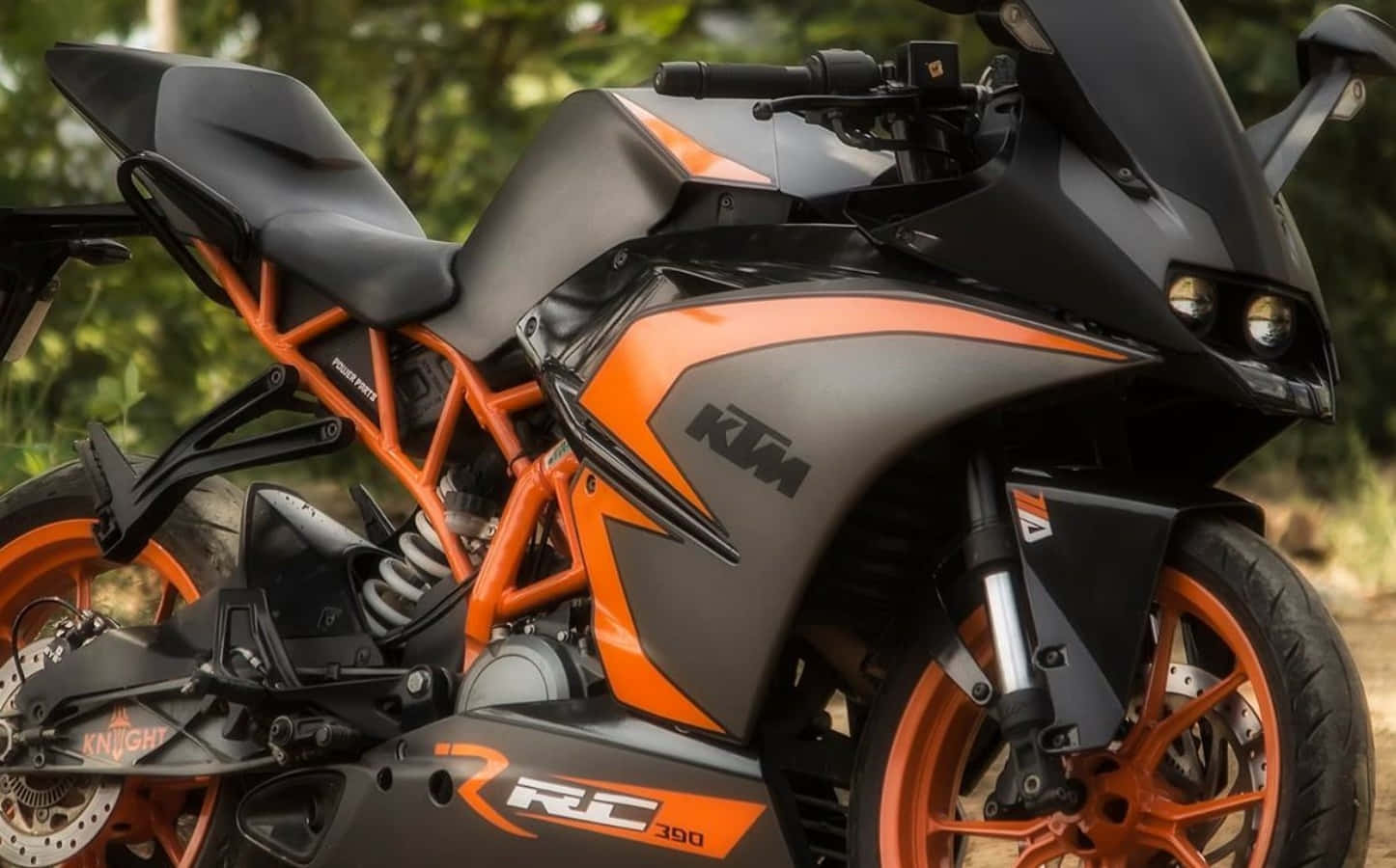 機車 桌布 壁紙 — 一台時尚黑色橙色KTM RC 390機車，外露車架及運動型設計，停放在戶外。