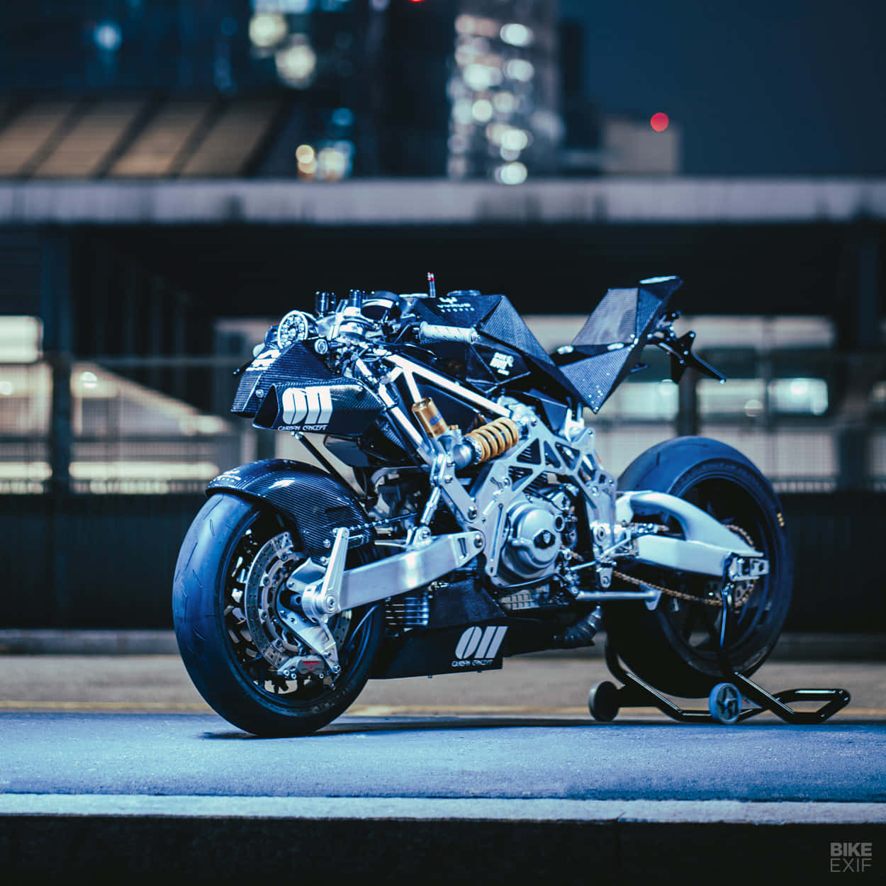 Vyrus Motorcycle 桌布 壁紙 — 一台未來感十足的黑色機車，暴露著機械細節，在夜晚的城市街道上，處於冷藍色燈光下。
