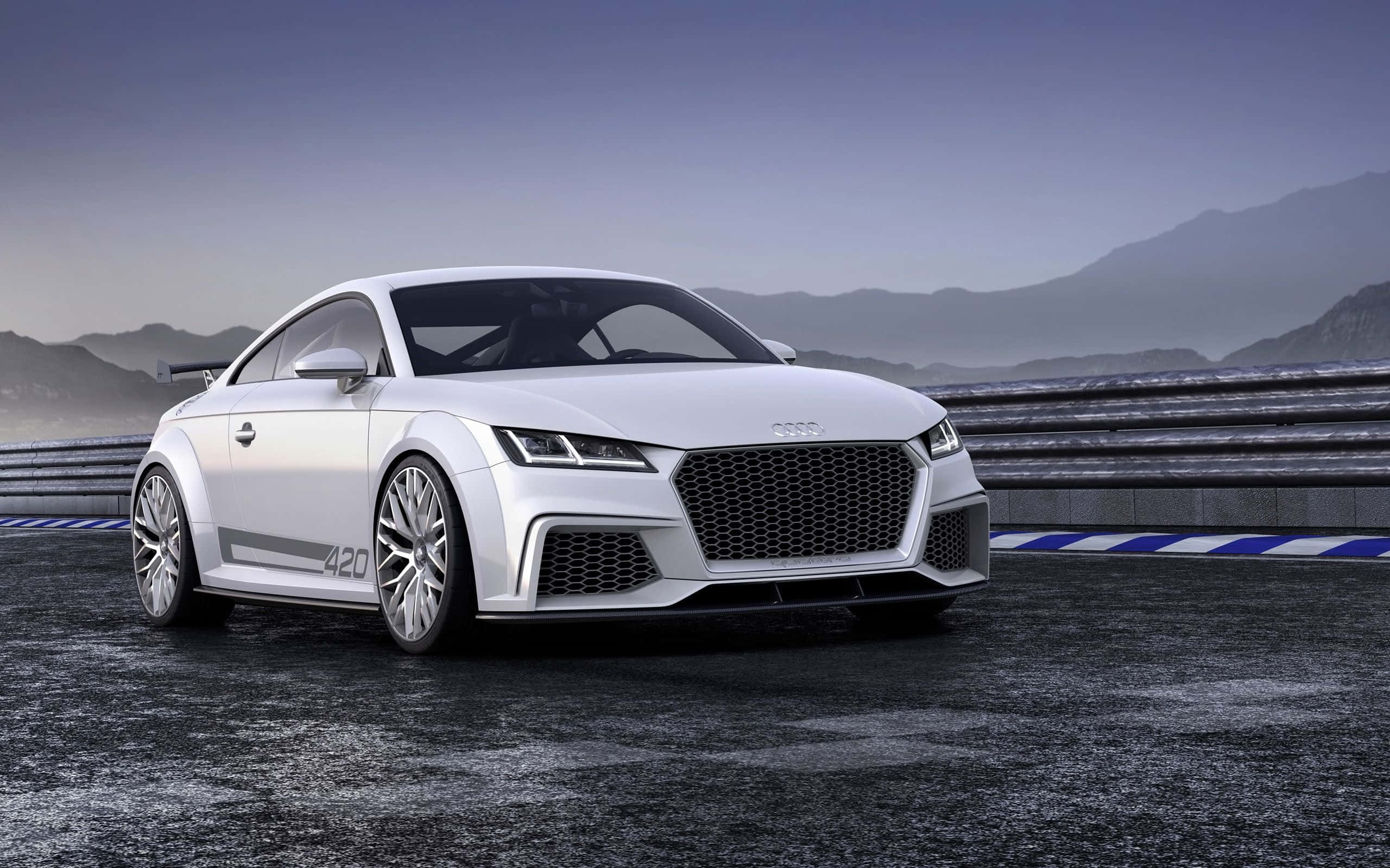 Audi Tt 桌布 壁紙 — 一台流線型白色奧迪TT RS跑車，在陰天下以山巒為背景，停泊在濕滑的賽道上。