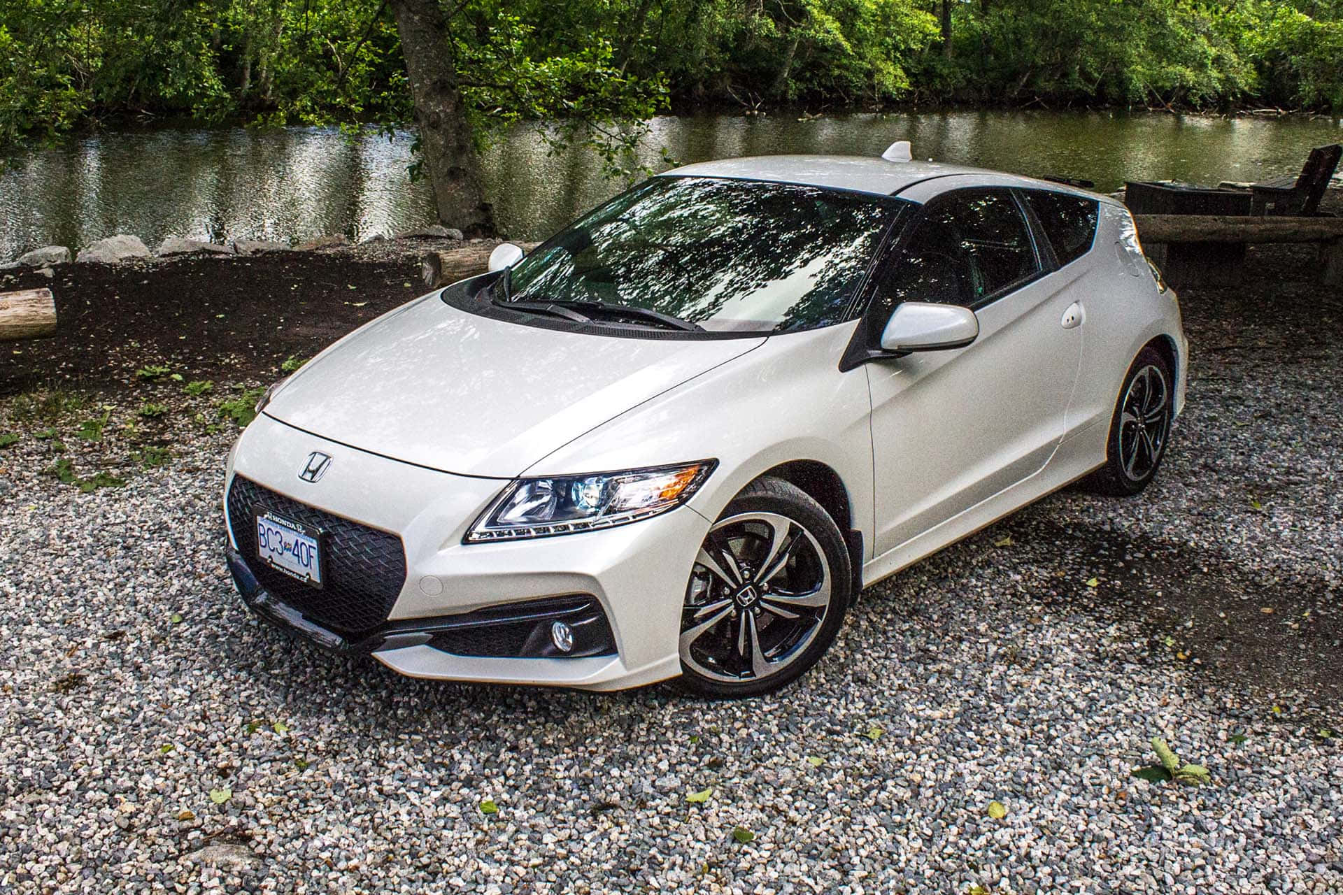 Honda Cr-z 桌布 壁紙 — 一台流線型白色本田S2000跑車停泊在碎石上，旁邊是平靜的河流，四周環繞著茂密的綠樹。