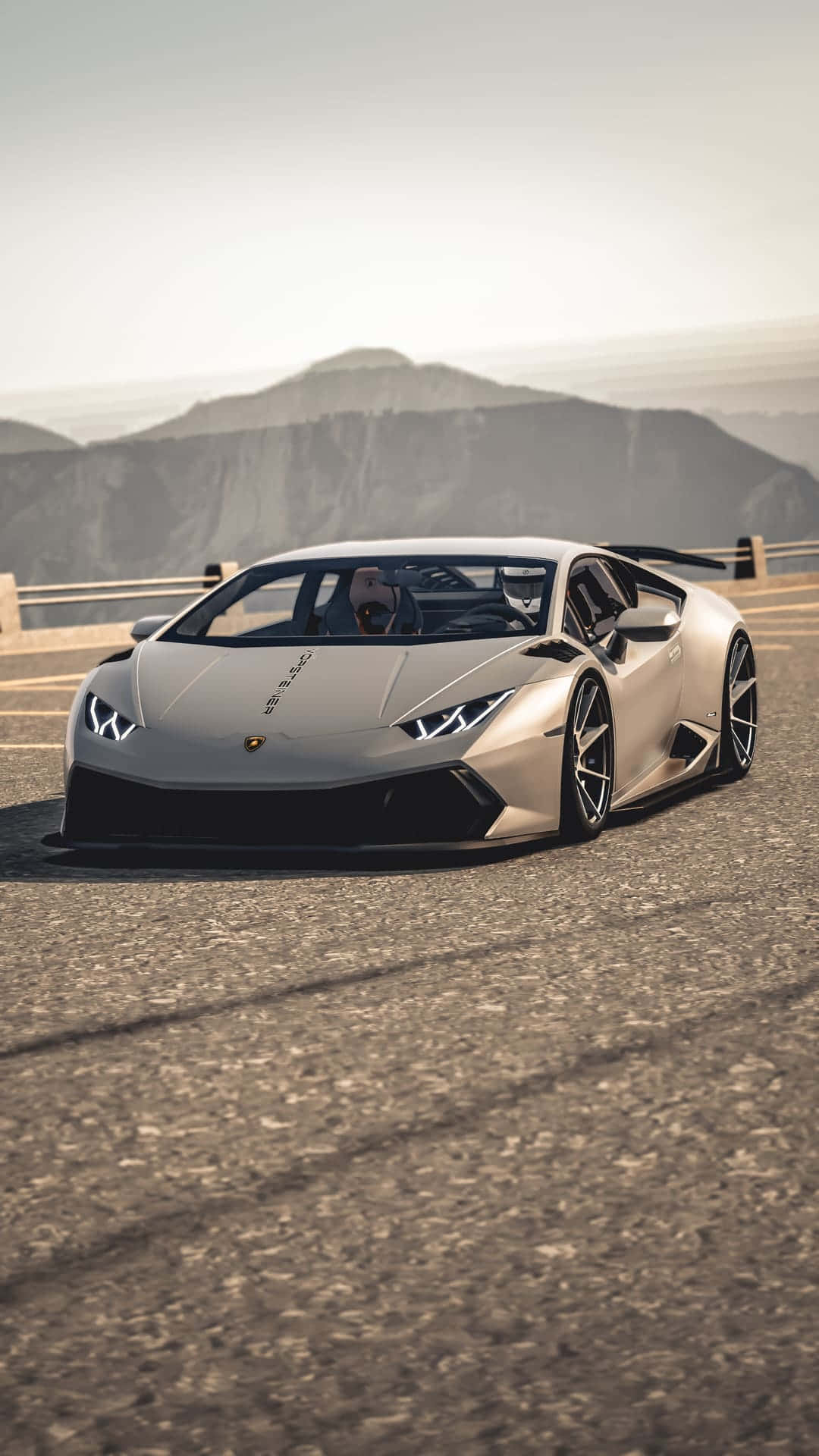 Pixel 3xl Lamborghini 桌布 壁紙 — 一台流線型的銀色藍寶堅尼Huracán停放在山路上，遠方山峰在朦朧天空下若隱若現。