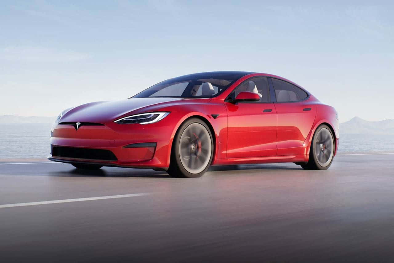 Hybrid Car 桌布 壁紙 — 一台流線型紅色Tesla Model S沿著海岸道路行駛，海洋與遠山在晴朗天空下清晰可見。