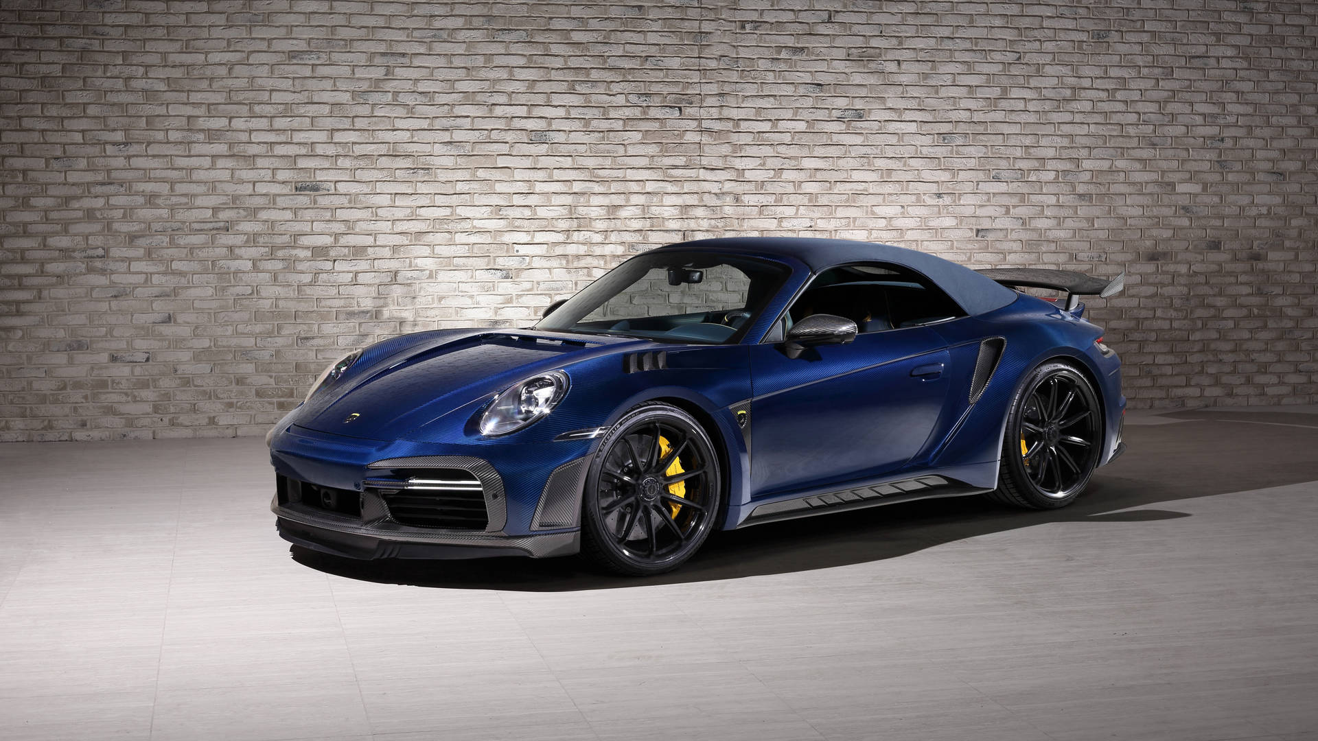 藍色保時捷911 Turbo S配備黃色制動卡鉗，以磚牆為背景。 — 保時捷 GIF 壁紙