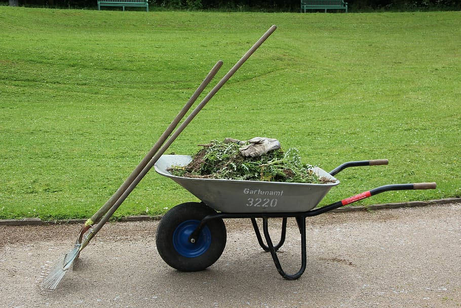 Garden 桌布 壁紙 — 一台灰色手推車裝滿了園藝剪枝和工具，擱在碎石小徑上，旁邊是翠綠的草坪。