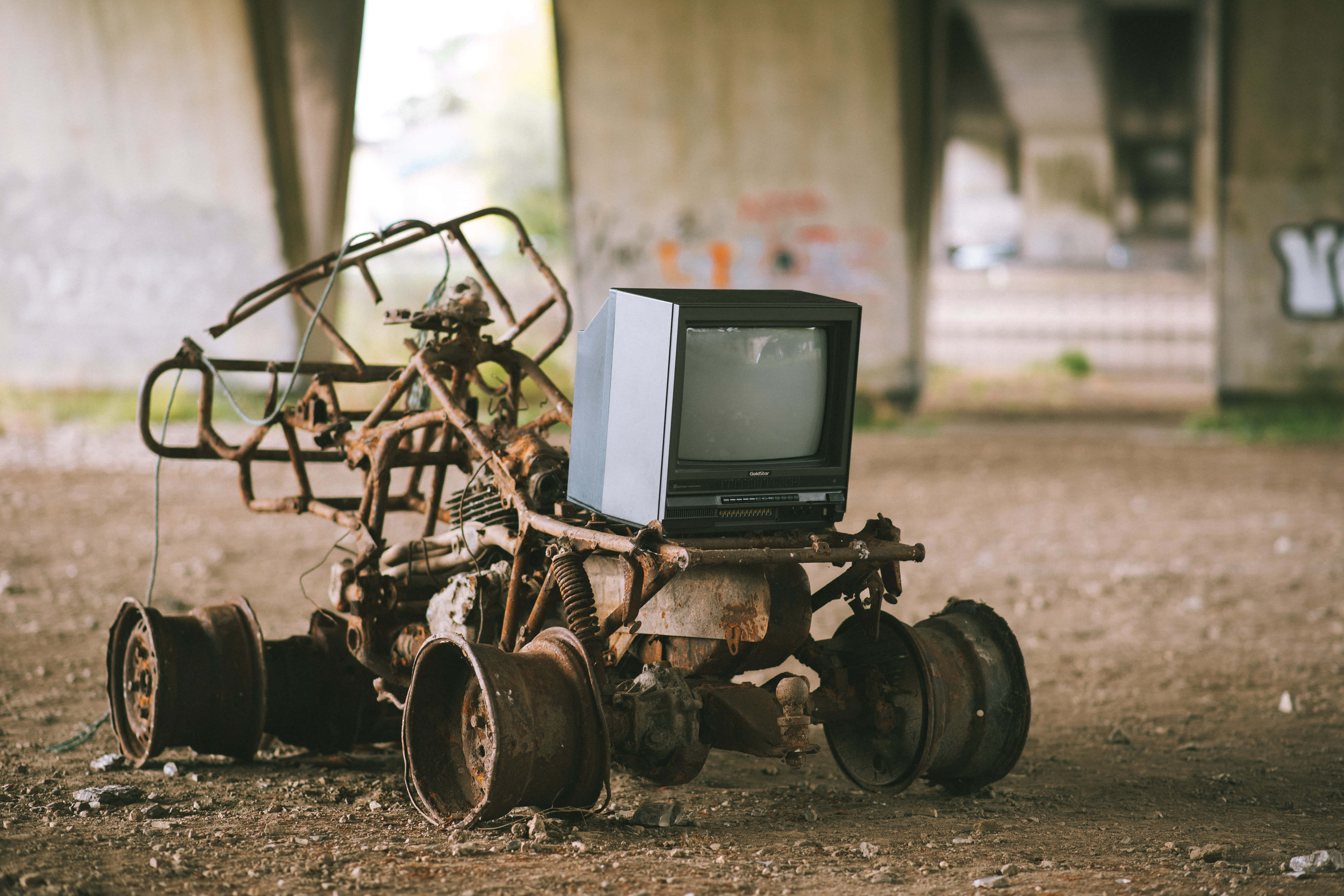 television 桌布 壁紙 — 一台生鏽破爛的卡丁車，車架上放著一台復古電視，被遺棄在混凝土天橋下。