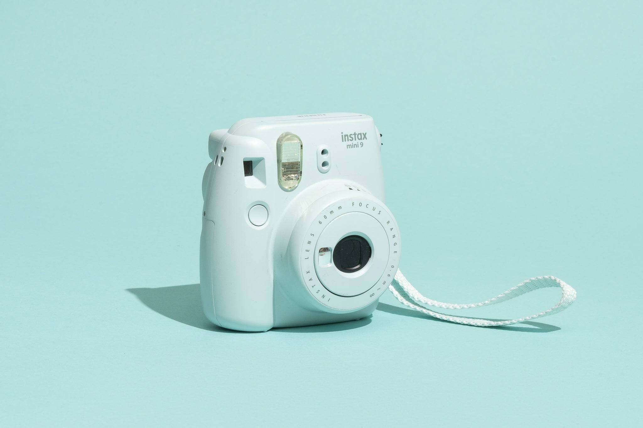 相機 桌布 壁紙 — 一台白色 Fujifilm Instax Mini 9 即時相機居中放置在純薄荷綠色背景上，帶有柔和陰影。