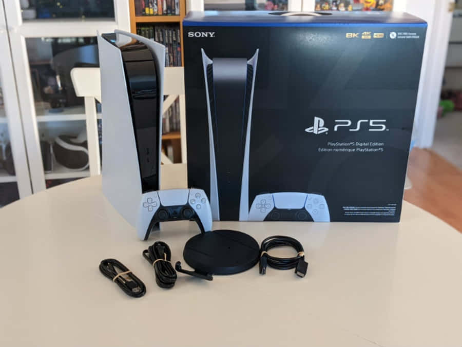 PS5 動態圖片 桌布 壁紙 — 一台白色 PlayStation 5 Digital Edition 主機及其包裝盒放在桌上，附有控制器線纜和光碟機轉接器。