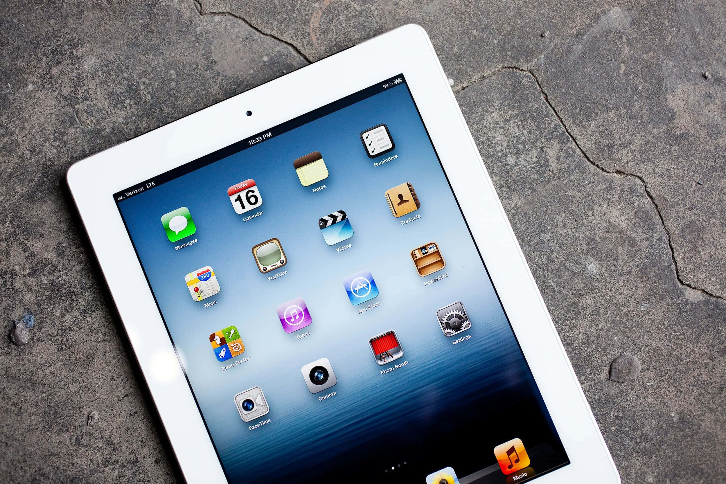 iPad 桌布 壁紙 — 一台白色iPad顯示iOS應用程式，放置在裂開的灰色混凝土表面上。