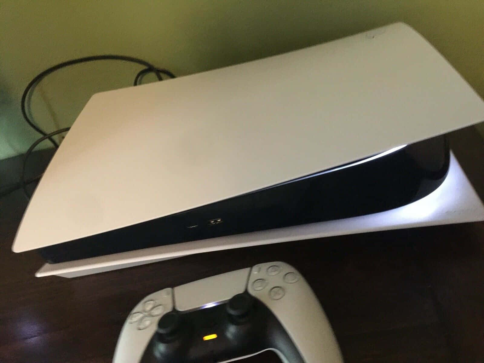 PlayStation 桌布 壁紙 — 一台白色PlayStation 5主機帶有發光燈光，放置在深色木質表面上，旁邊是其匹配的控制器。
