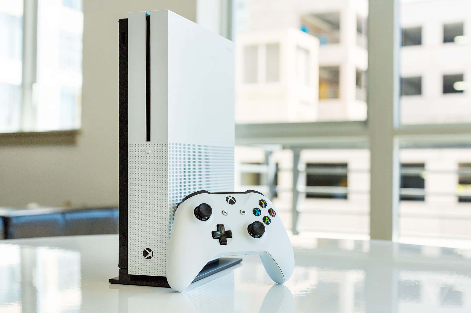 一台白色Xbox One主機放在桌上 壁紙