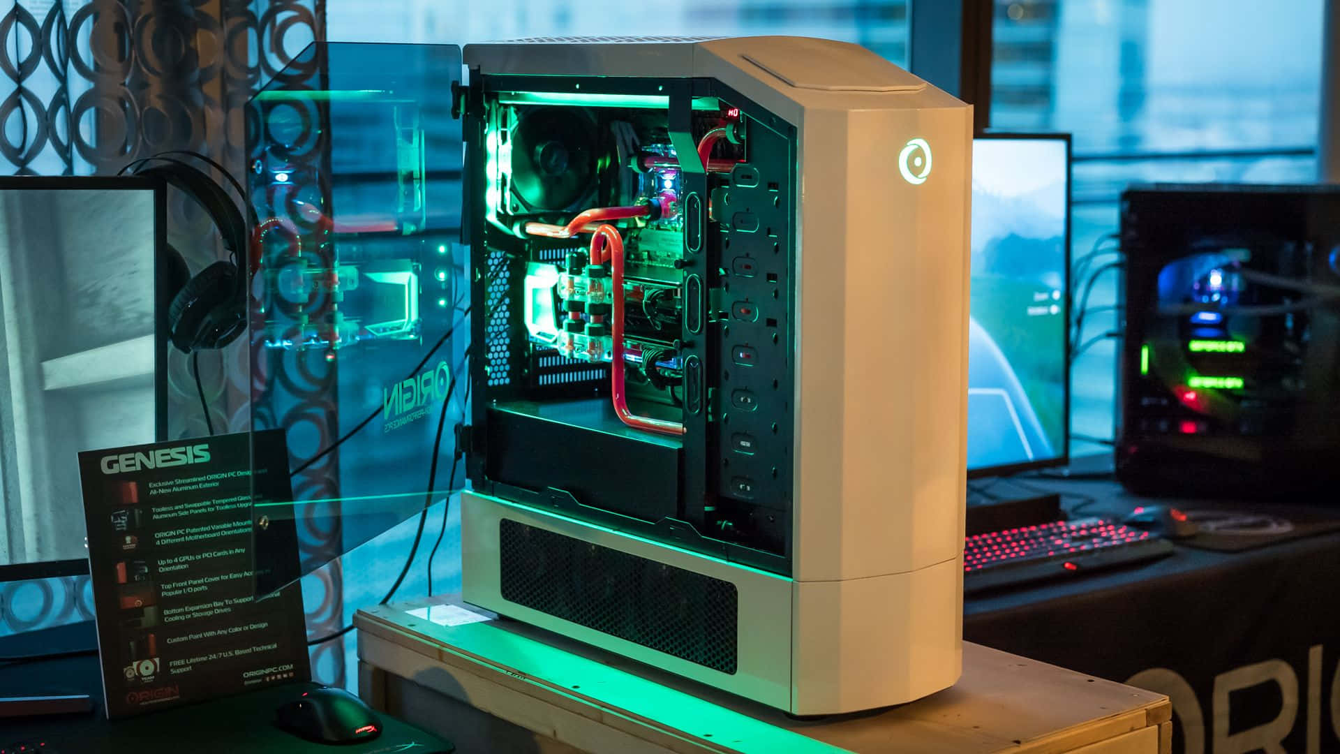 Gaming Pc 桌布 壁紙 — 一台白色遊戲電腦，內部發出綠色光芒，放置在木製支架上，周圍環繞著顯示器和周邊設備，在科技展覽中展示。