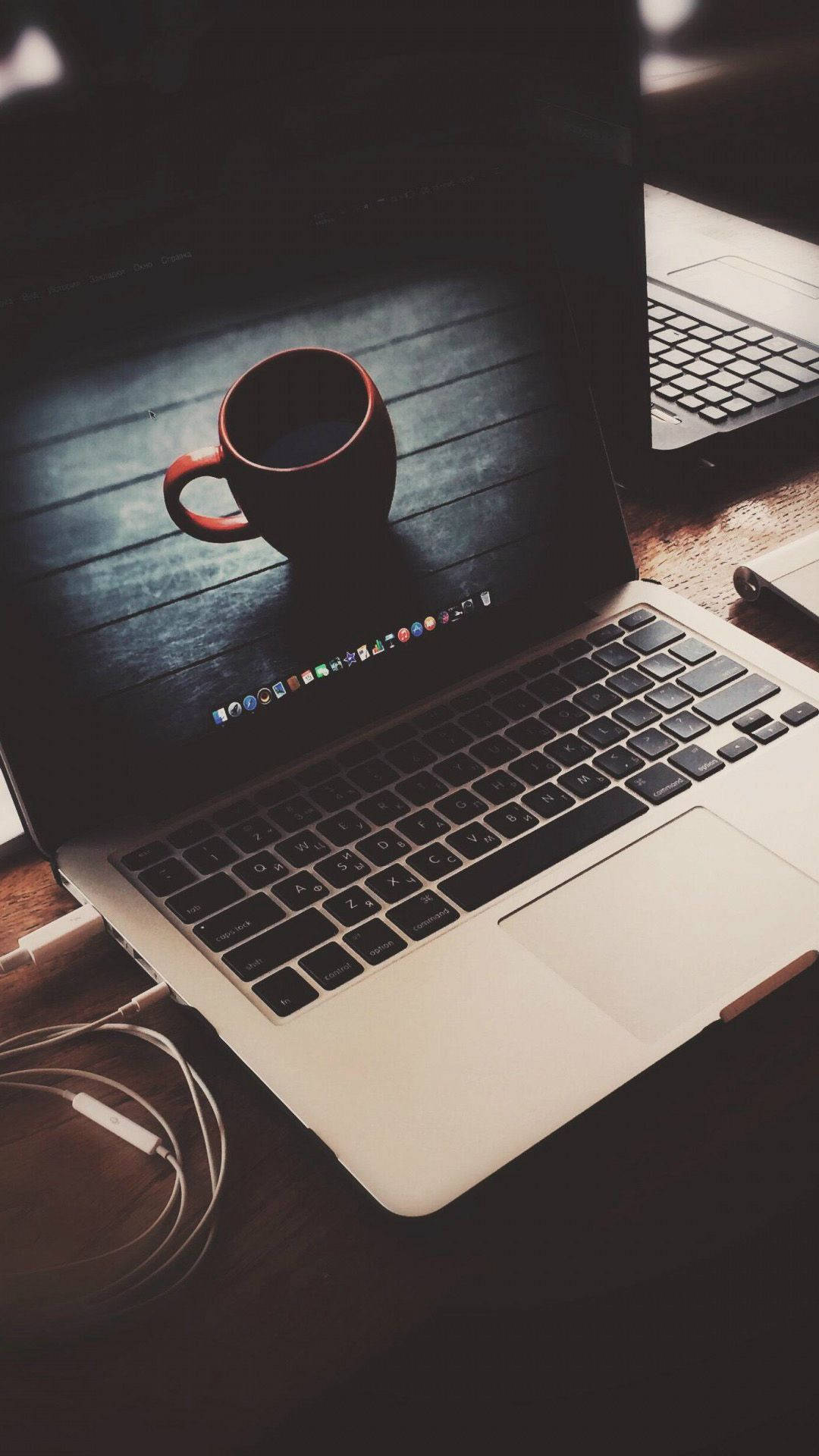 MacBook 動態圖片 桌布 壁紙 — 一台筆記型電腦放在木桌上，螢幕上顯示一個深色咖啡杯，附近有電線和筆記本。