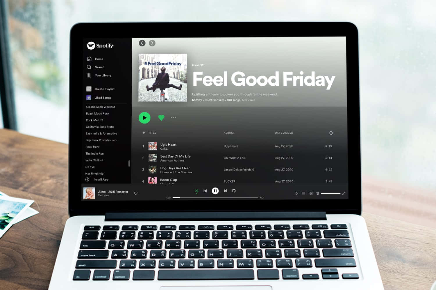 攝影 桌布 壁紙 — 一台筆記型電腦顯示名為「Feel Good Friday」的 Spotify 播放清單，專輯藝術中有一個穿黑色西裝的人坐在腳踏車上。