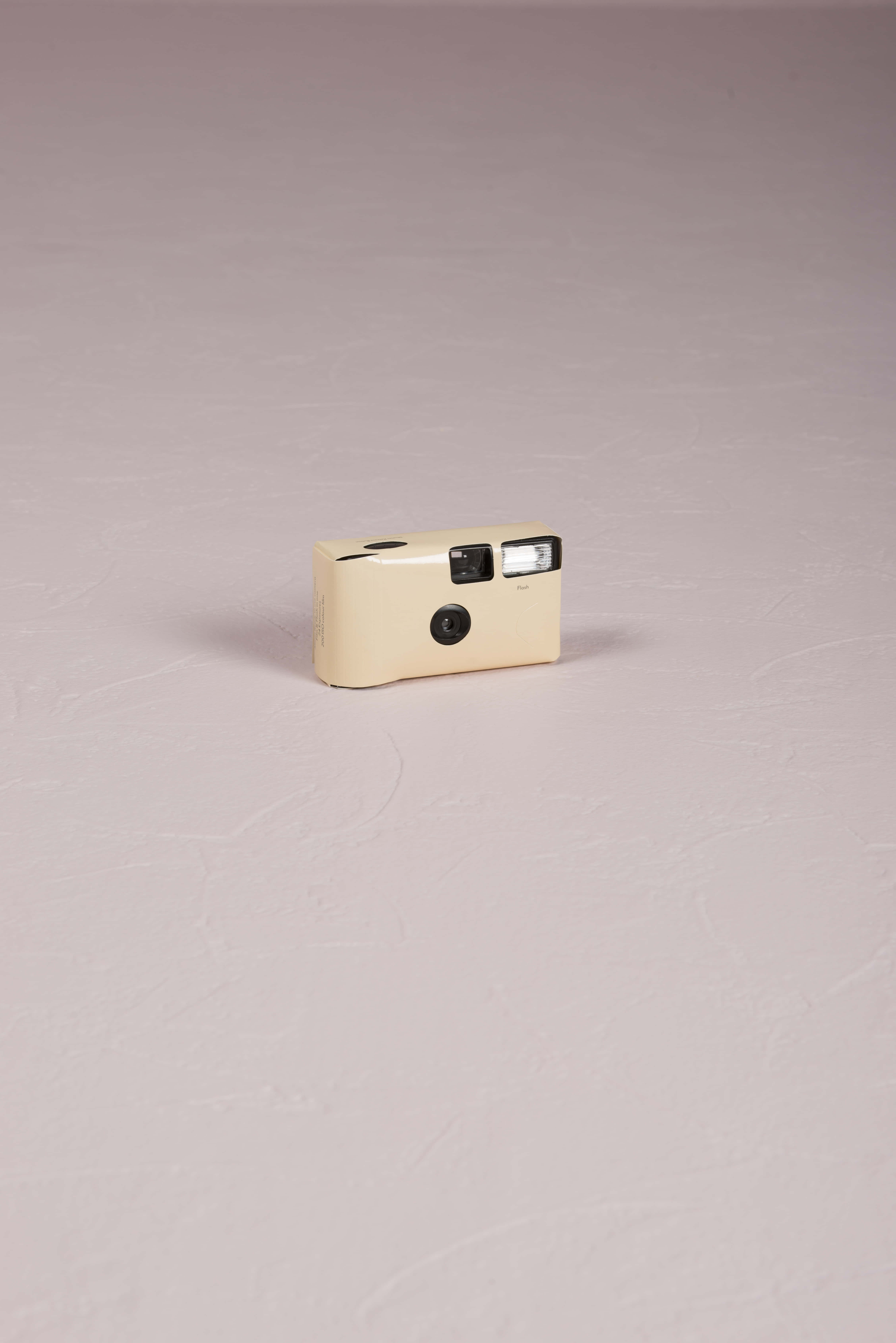 Disposable Camera 桌布 壁紙 — 一台米白色復古底片相機在柔和工作室燈光下獨自放在有紋理的紫紅色表面上。