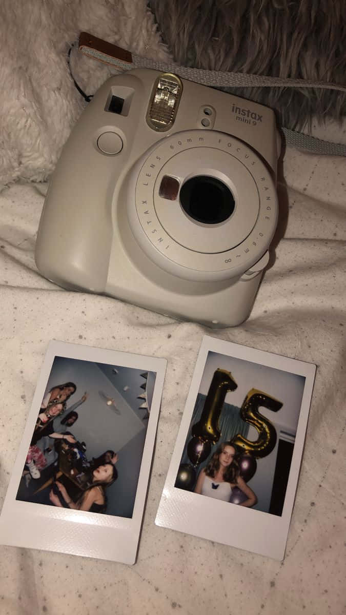 Aesthetic Polaroid 桌布 壁紙 — 一台米色拍立得相機放在一張毛茸茸的白色毯子上，旁邊有兩張列印出來的照片。