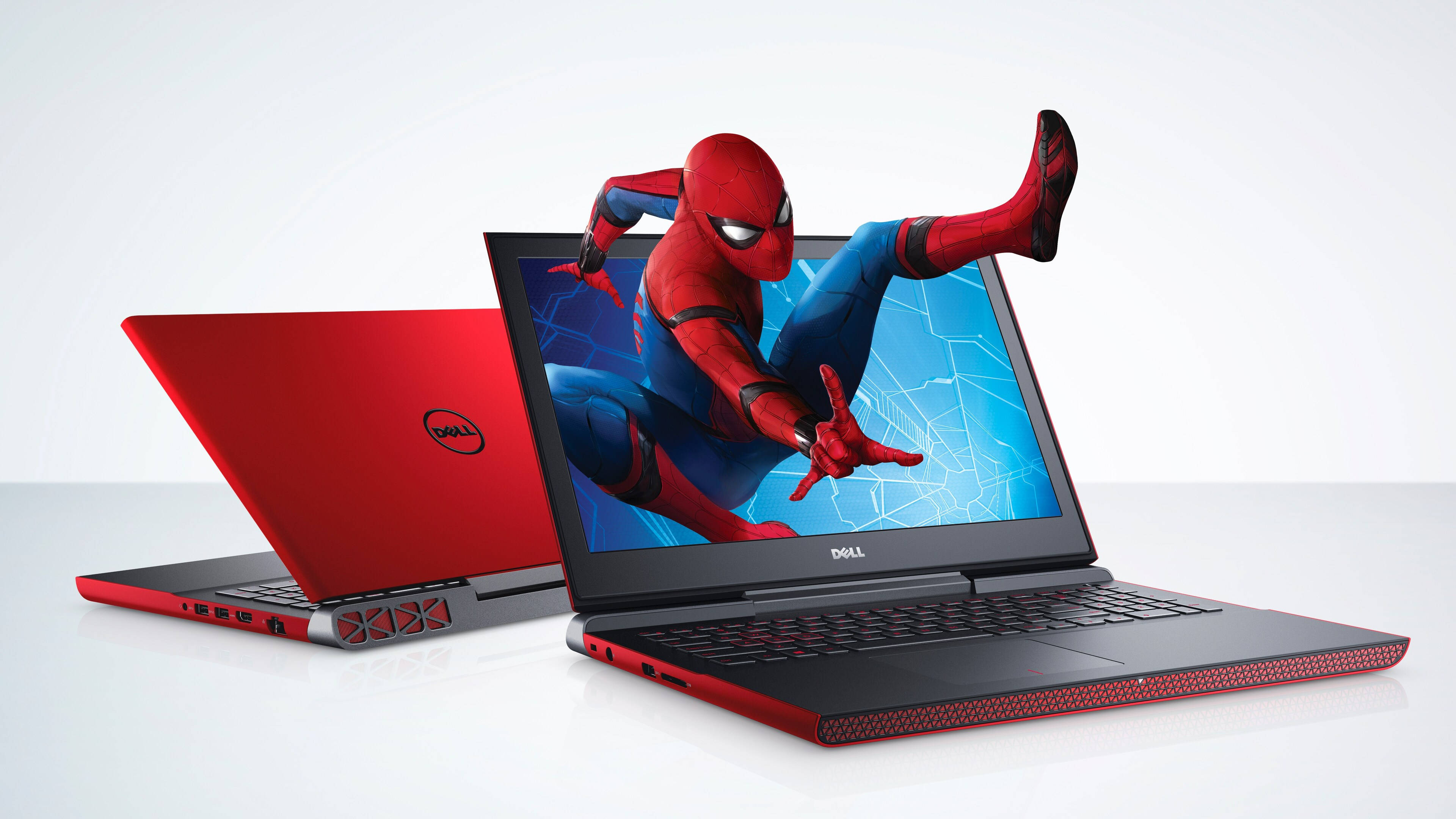dell 4K 桌布 壁紙 — 一台紅色Dell筆記型電腦在潔白的工作室背景上顯示動態的蜘蛛人動作場景。