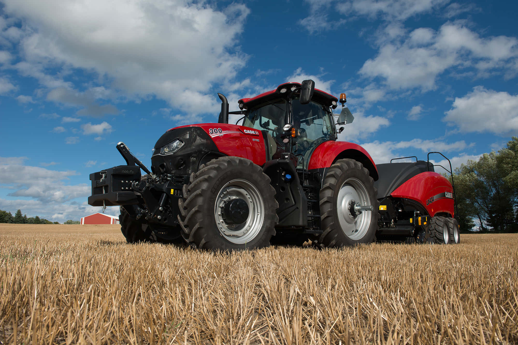 Tractor 桌布 壁紙 — 一台紅色的Case IH拖拉機站在金色收割過的田野中，下方是明亮的藍天和蓬鬆的白雲。
