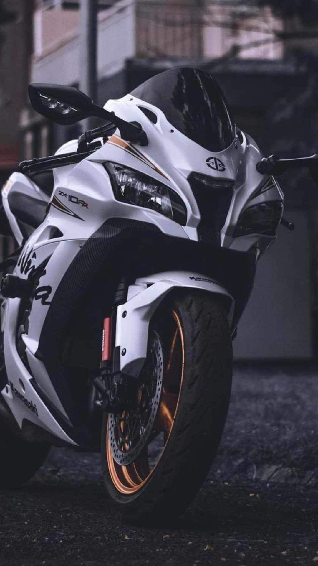 Superbike 桌布 壁紙 — 一台線條流暢的白色運動機車，配金色輪圈，停放在昏暗燈光下潮濕的都市街道上。