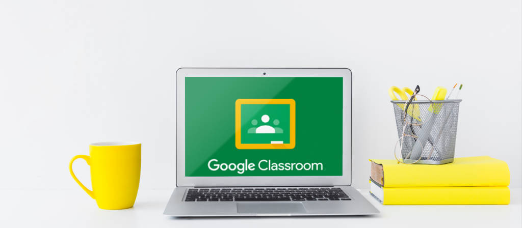 學校 桌布 壁紙 — 一台銀色筆記型電腦在綠色螢幕上顯示Google Classroom，旁邊有一個黃色杯子、疊起的黃色資料夾和筆筒。