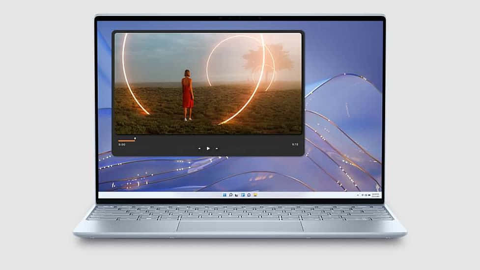 Dell 桌布 壁紙 — 一台銀色筆記型電腦顯示一段影片，片中一個穿紅色衣服的人站在田野中，背景是日落時分發光的圓形燈光。