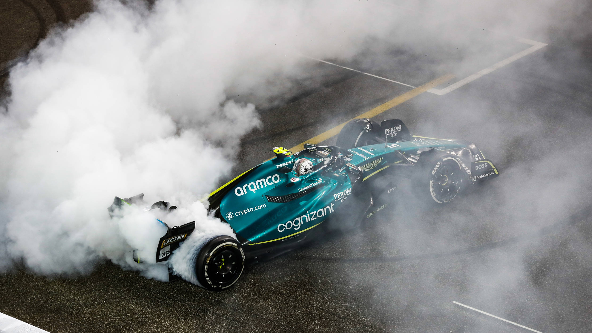 酷炫F1 桌布 壁紙 — 一台青綠色一級方程式賽車在賽道上冒著白煙燒胎。