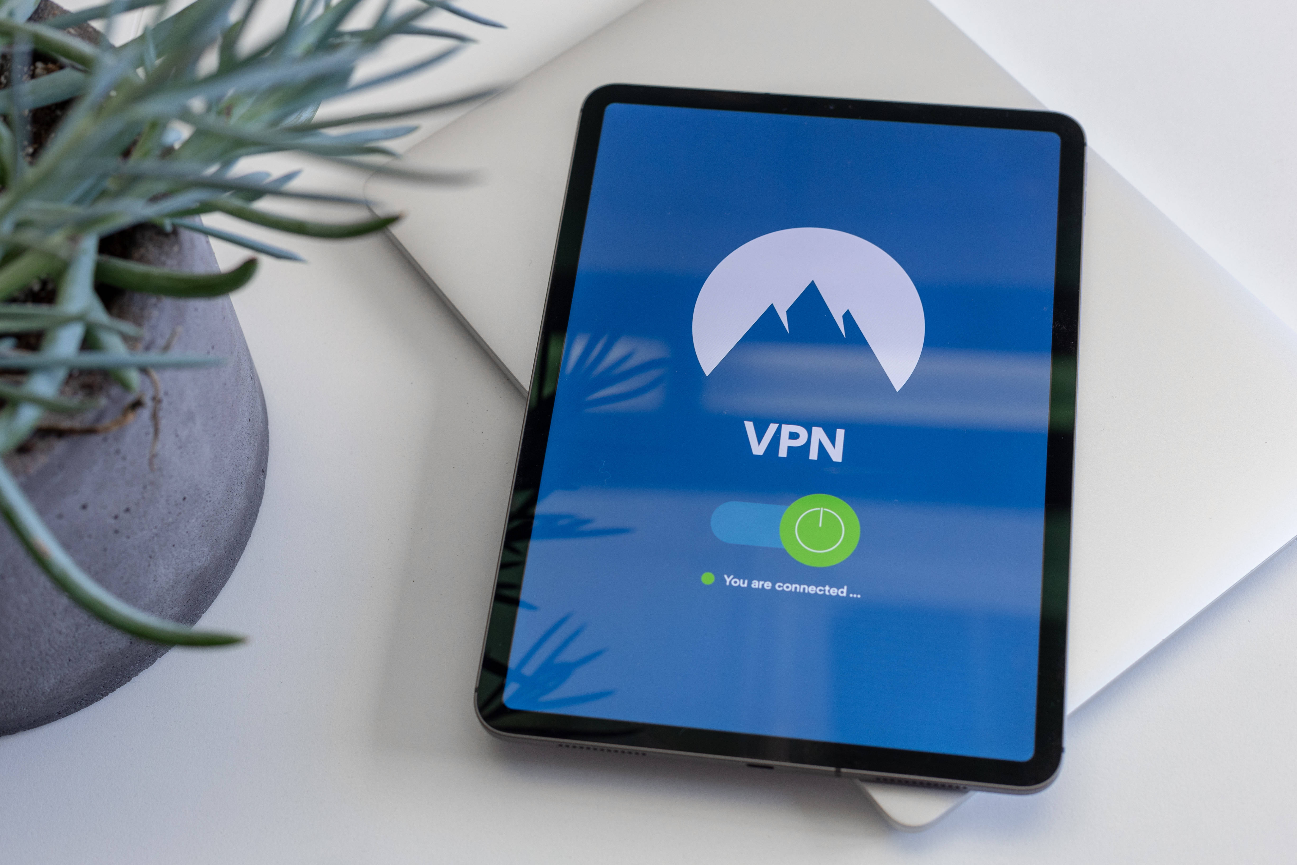 平板電腦 桌布 壁紙 — 一台顯示VPN連線畫面的平板電腦放在白色表面上，旁邊有一盆多肉植物。