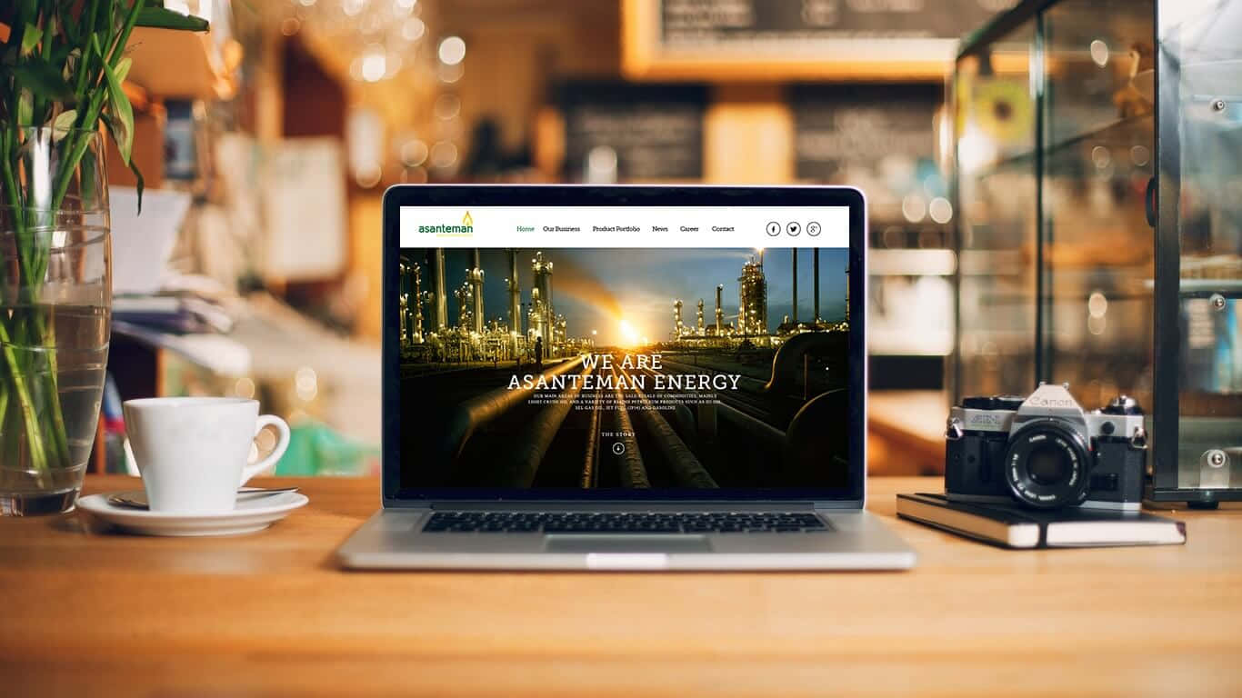 Website 桌布 壁紙 — 一台顯示能源公司網站的筆記型電腦放在舒適咖啡館的木桌上，旁邊有一杯咖啡和一部復古相機。