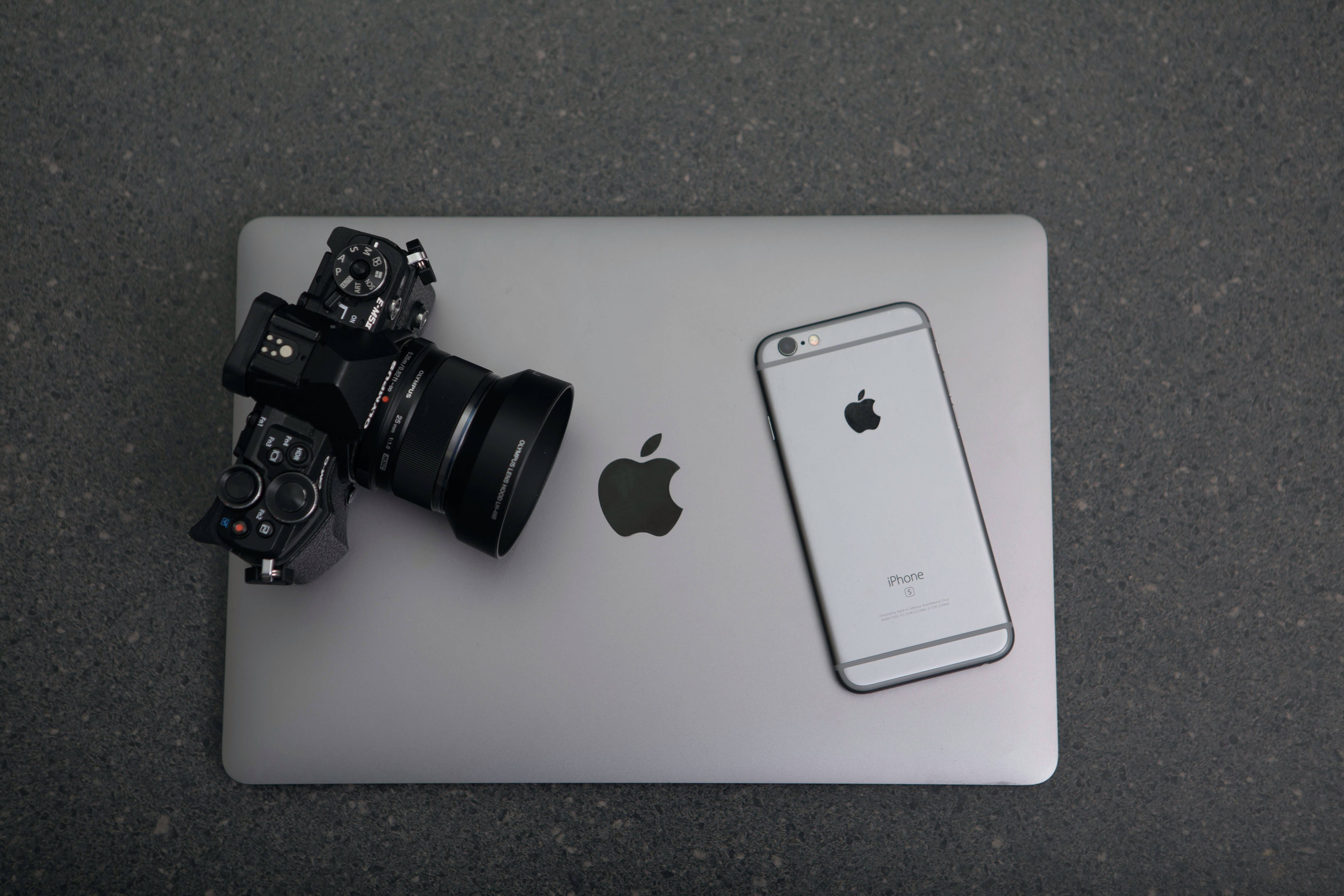 相機 桌布 壁紙 — 一台黑色單眼相機和銀色iPhone放在一台闔上的銀色MacBook上，置於灰色紋理表面。