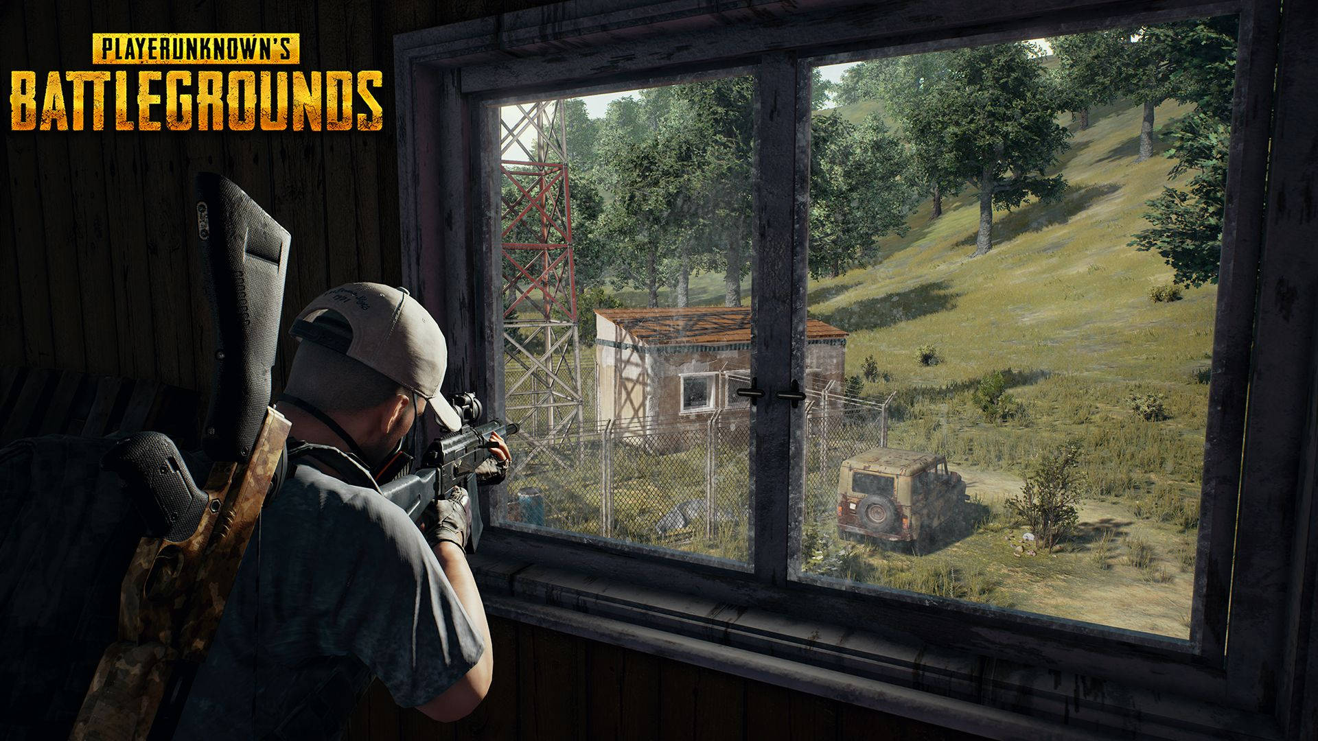 Pubg Logo 桌布 壁紙 — 一名《PUBG》玩家蹲在窗邊，用步槍瞄準遠處一個有圍欄的建築群，草地上有一輛生鏽的吉普車和一座塔。