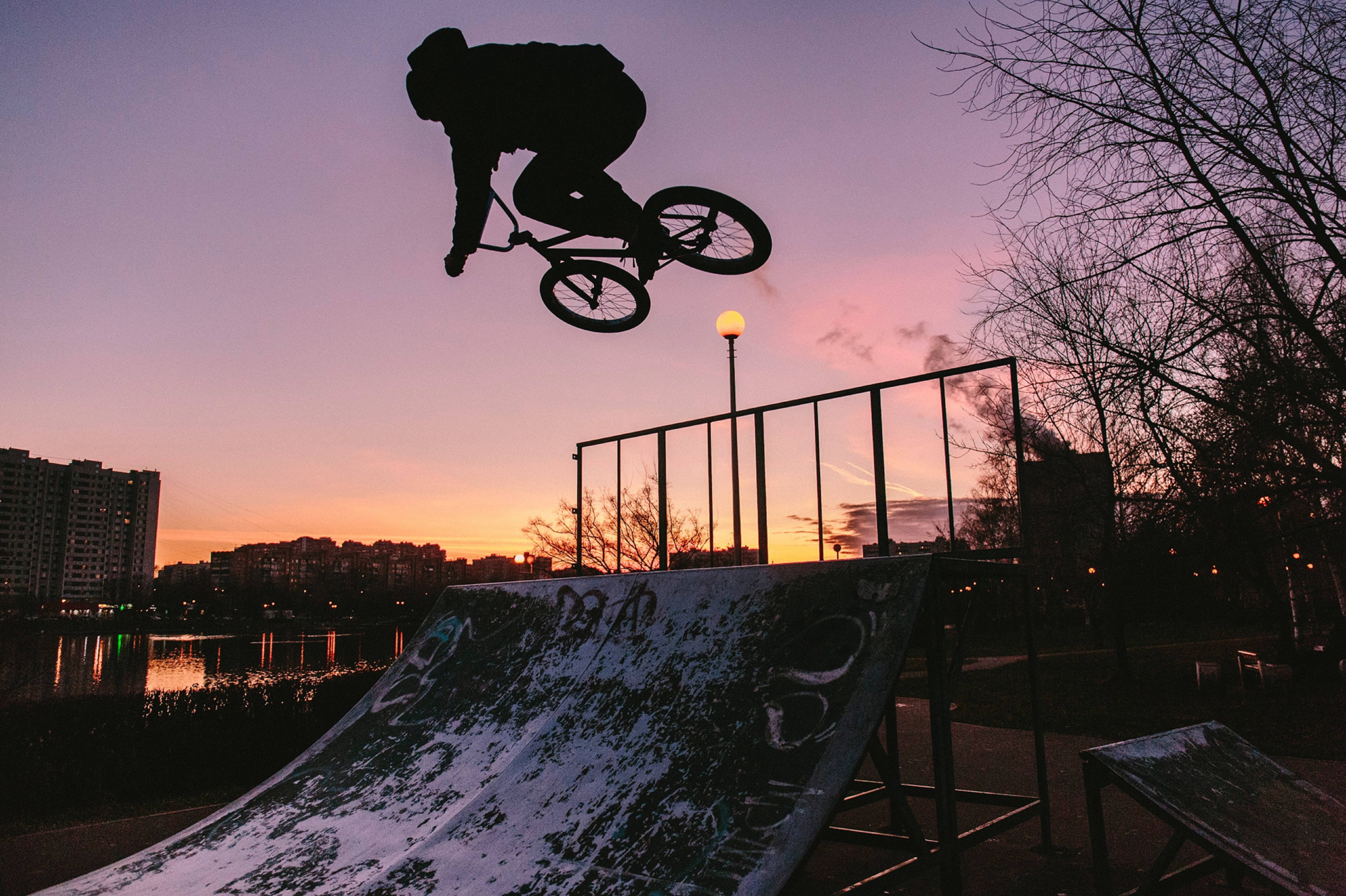 Extreme 桌布 壁紙 — 一名BMX車手在塗鴉覆蓋的坡道上空剪影，背景是充滿活力的紫色和橙色日落天空。