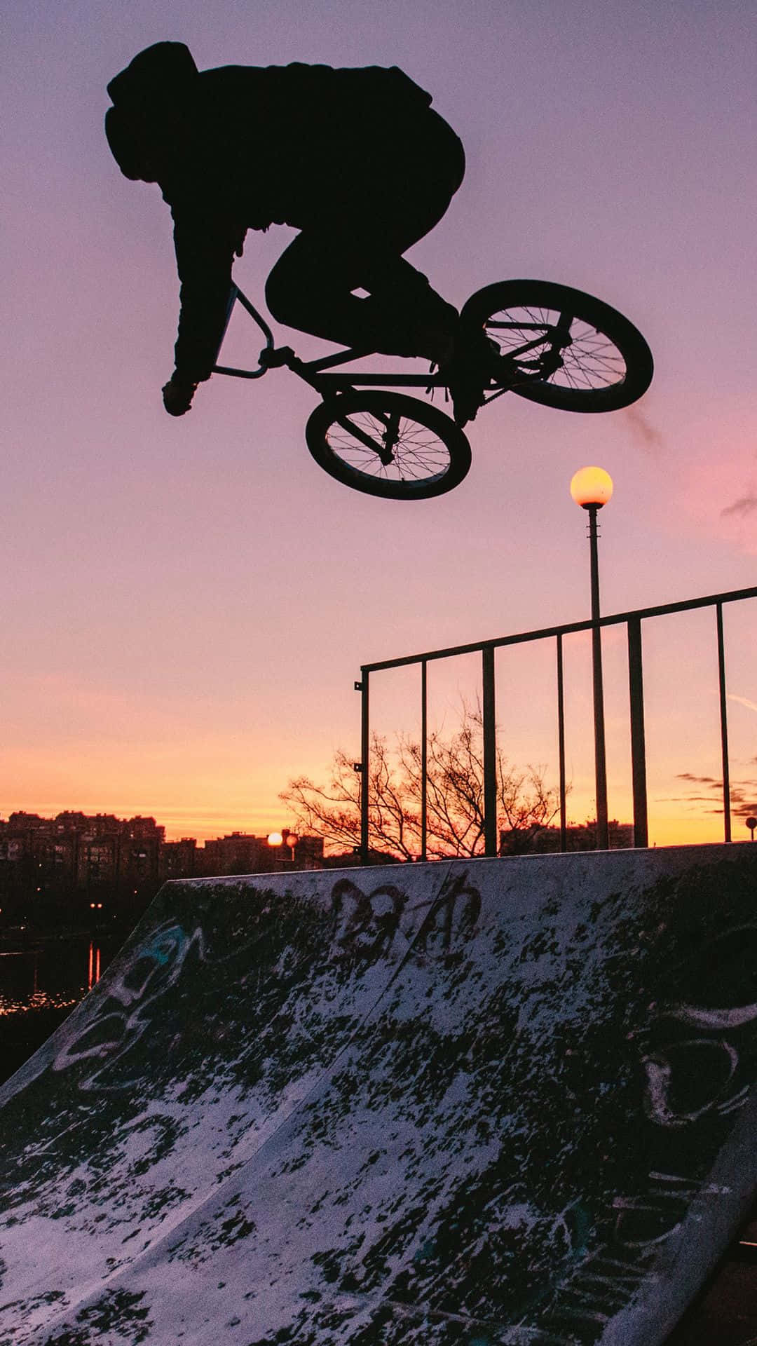 運動 桌布 壁紙 — 一名BMX車手在塗鴉覆蓋的坡道上空剪影，背景是充滿活力的日落天空。