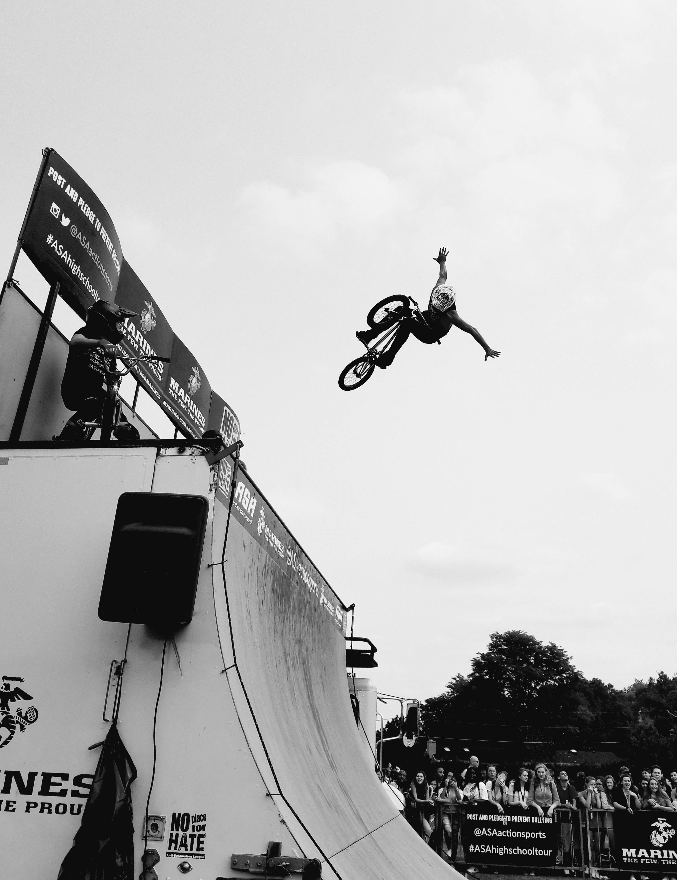 Brave 桌布 壁紙 — 一名BMX車手在斜坡上方騰空飛翔，觀眾從下方觀看，黑白動作鏡頭。