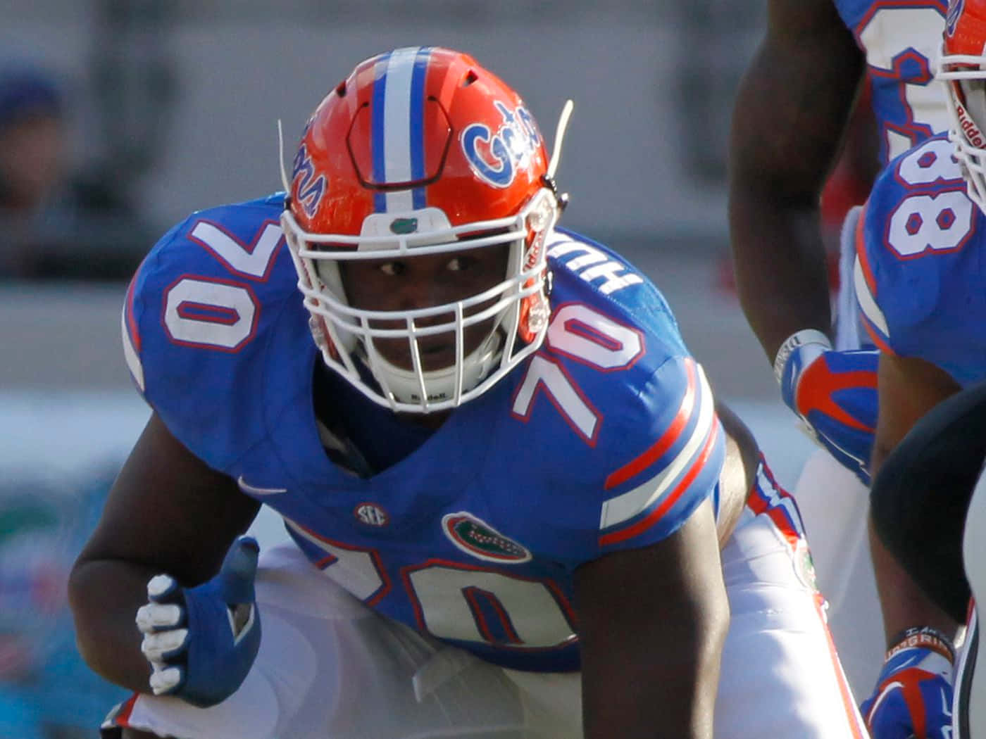 Florida Gators 桌布 壁紙 — 一名佛羅里達短吻鱷足球員身穿藍色和橙色裝備在比賽中激烈蹲下。