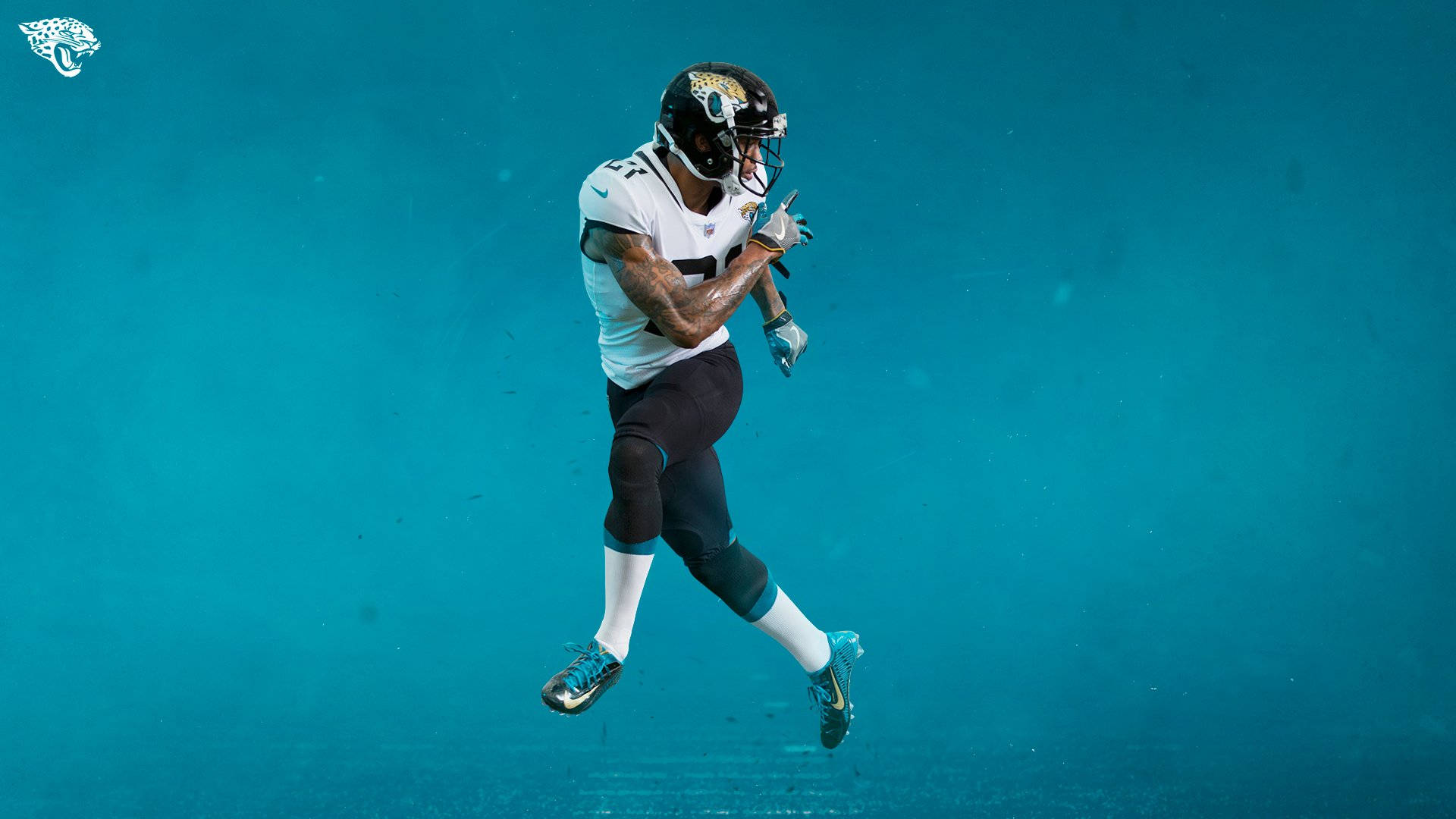 Jaguars 桌布 壁紙 — 一名傑克遜維爾美洲虎隊美式足球員在純青色背景上邁步中。