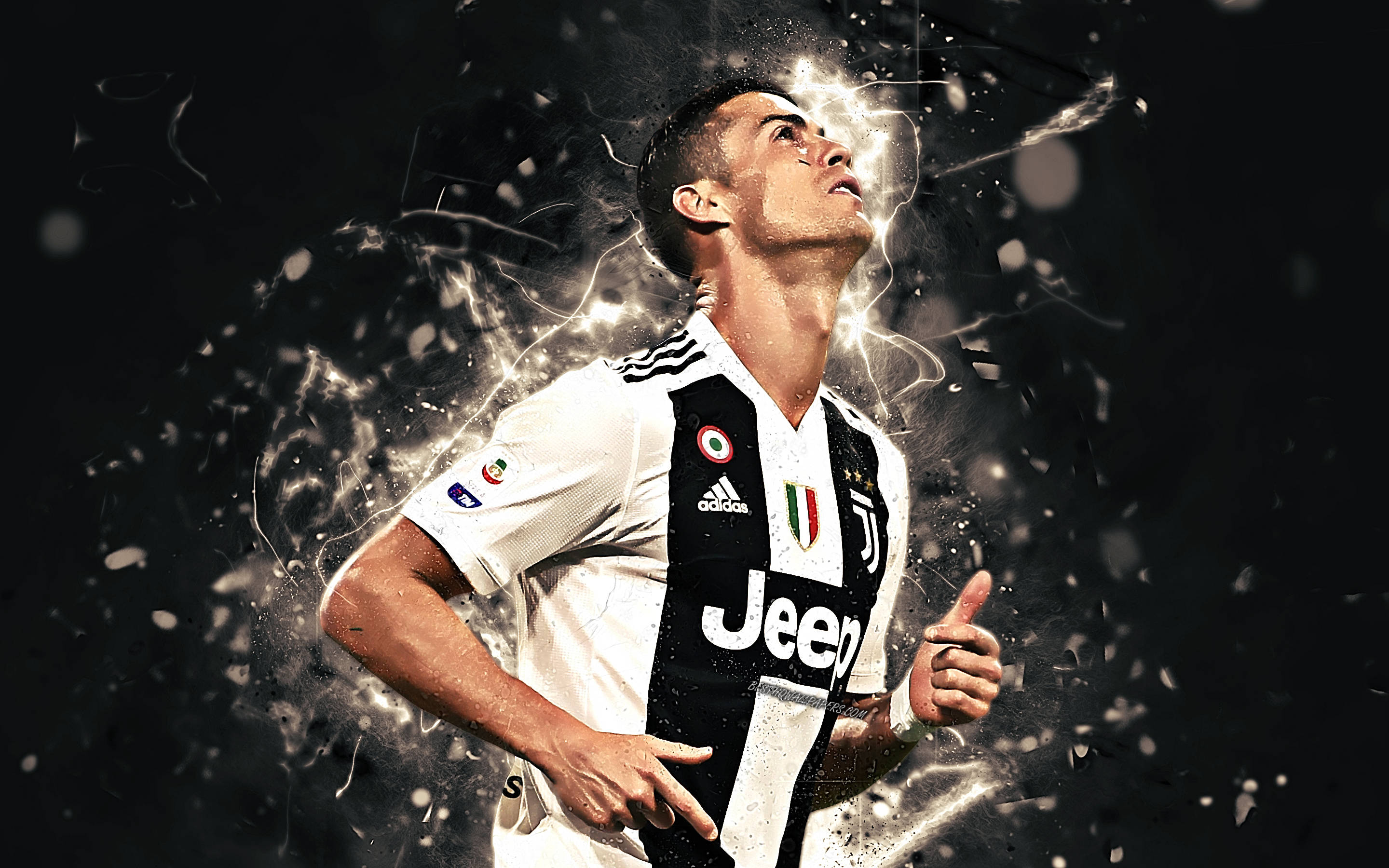 Ronaldo 桌布 壁紙 — 一名充滿活力的足球員身穿尤文圖斯球衣，在黑暗背景下抬頭仰望，電能和五彩紙屑在他周圍爆炸。
