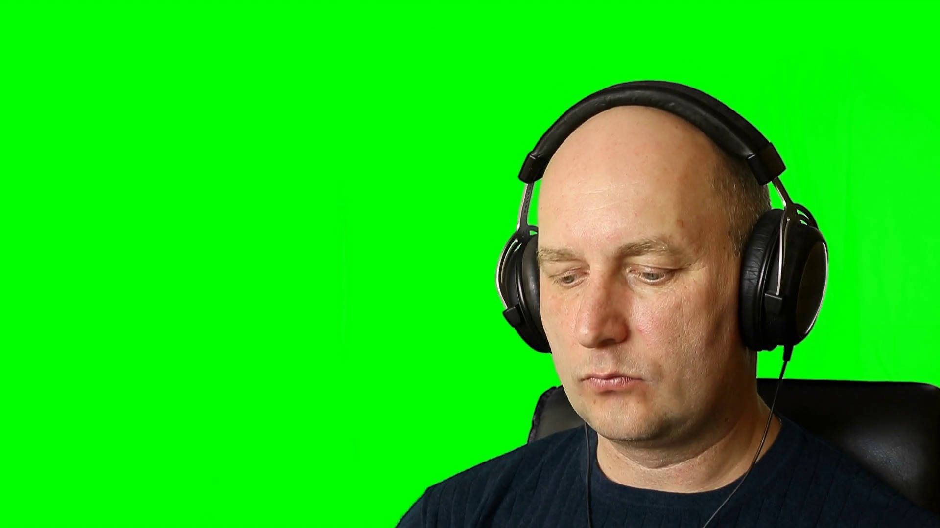 Green Screen 桌布 壁紙 — 一名光頭男子戴著黑色耳機坐在椅子上，背景是純綠色螢幕。