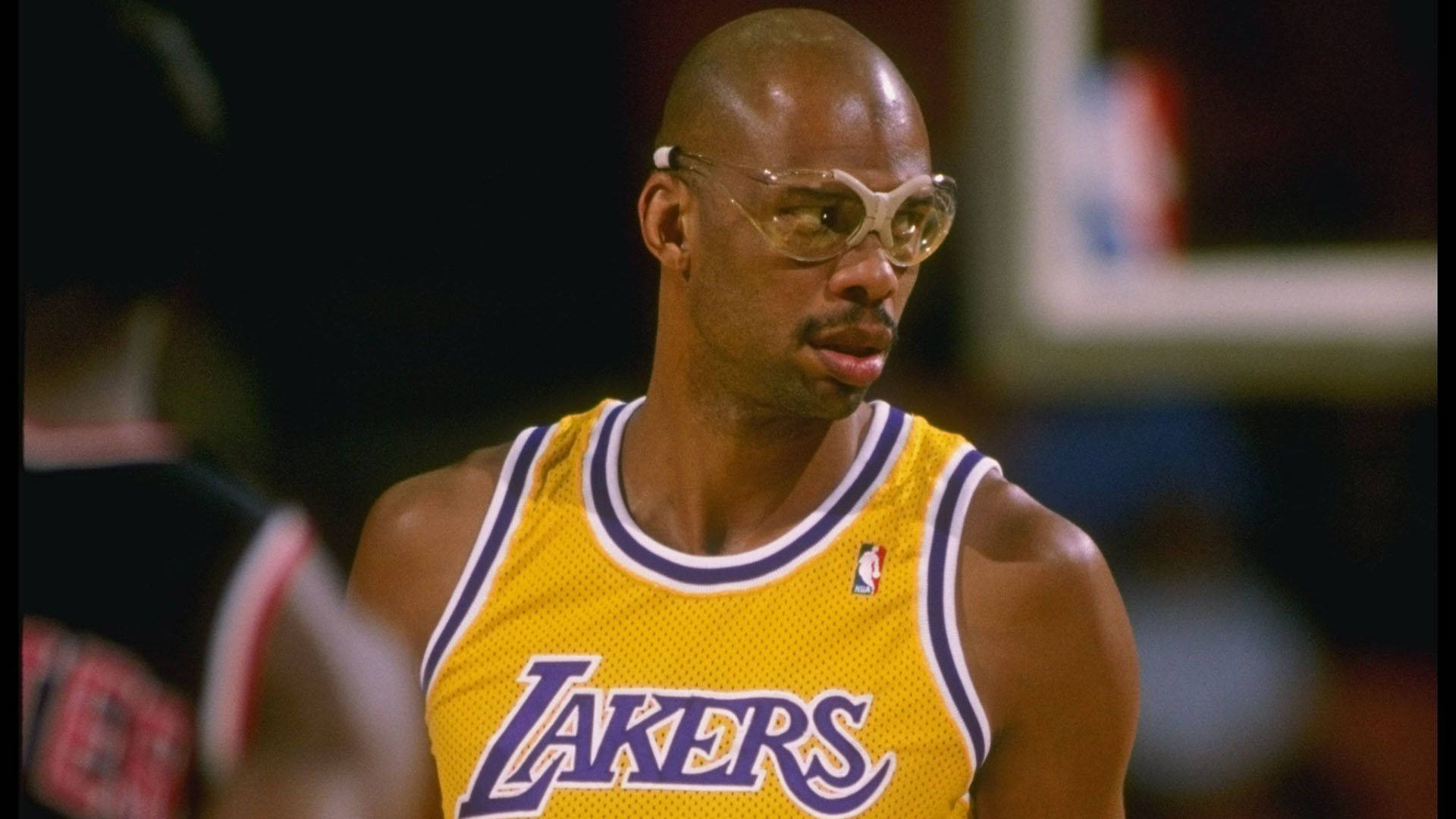 Kareem 桌布 壁紙 — 一名光頭籃球運動員在比賽中穿著黃色湖人隊球衣，戴著透明眼鏡的特寫。