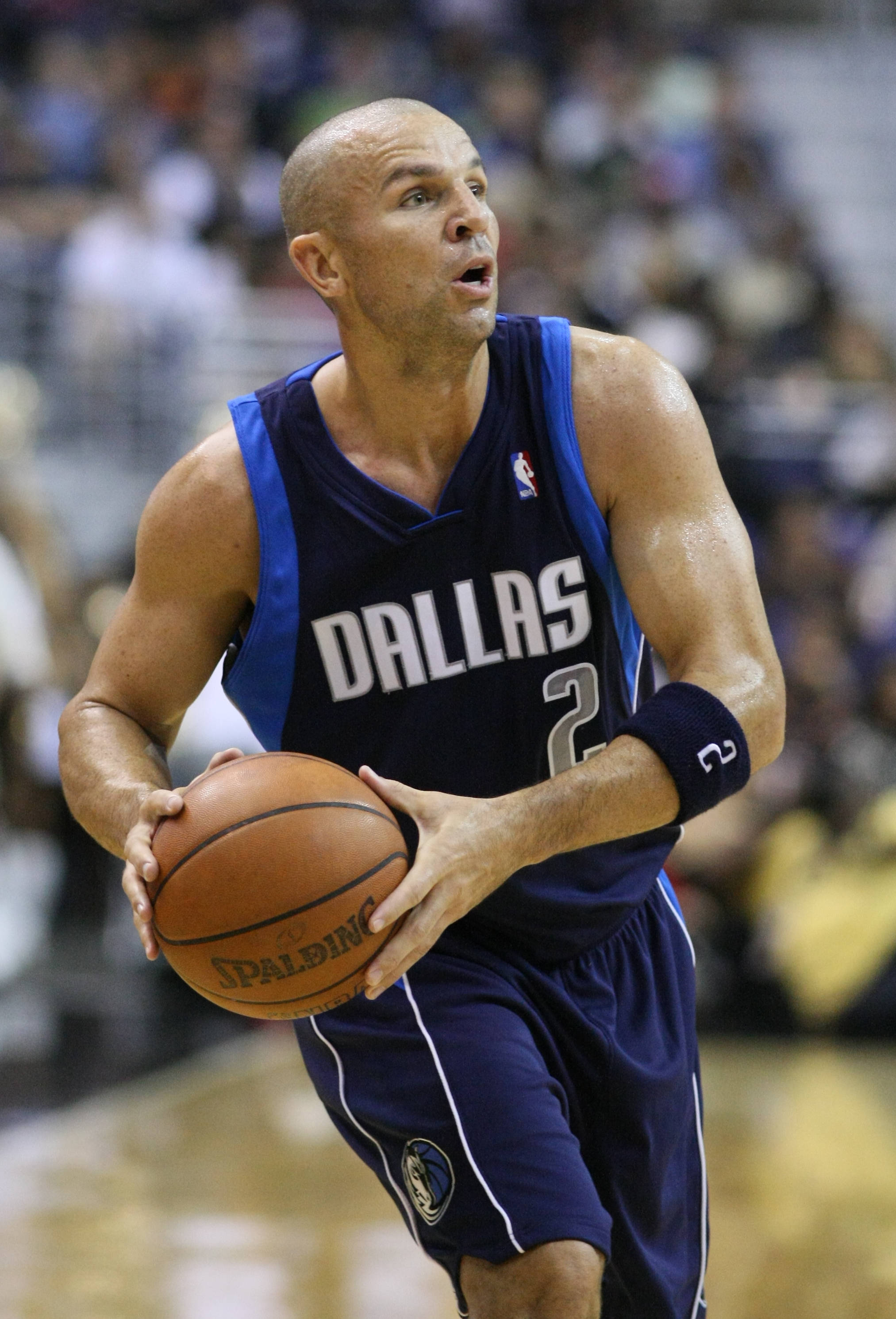 NBA 桌布 壁紙 — 一名光頭籃球運動員身穿達拉斯球衣，在明亮的場館燈光下於比賽中激烈運球。
