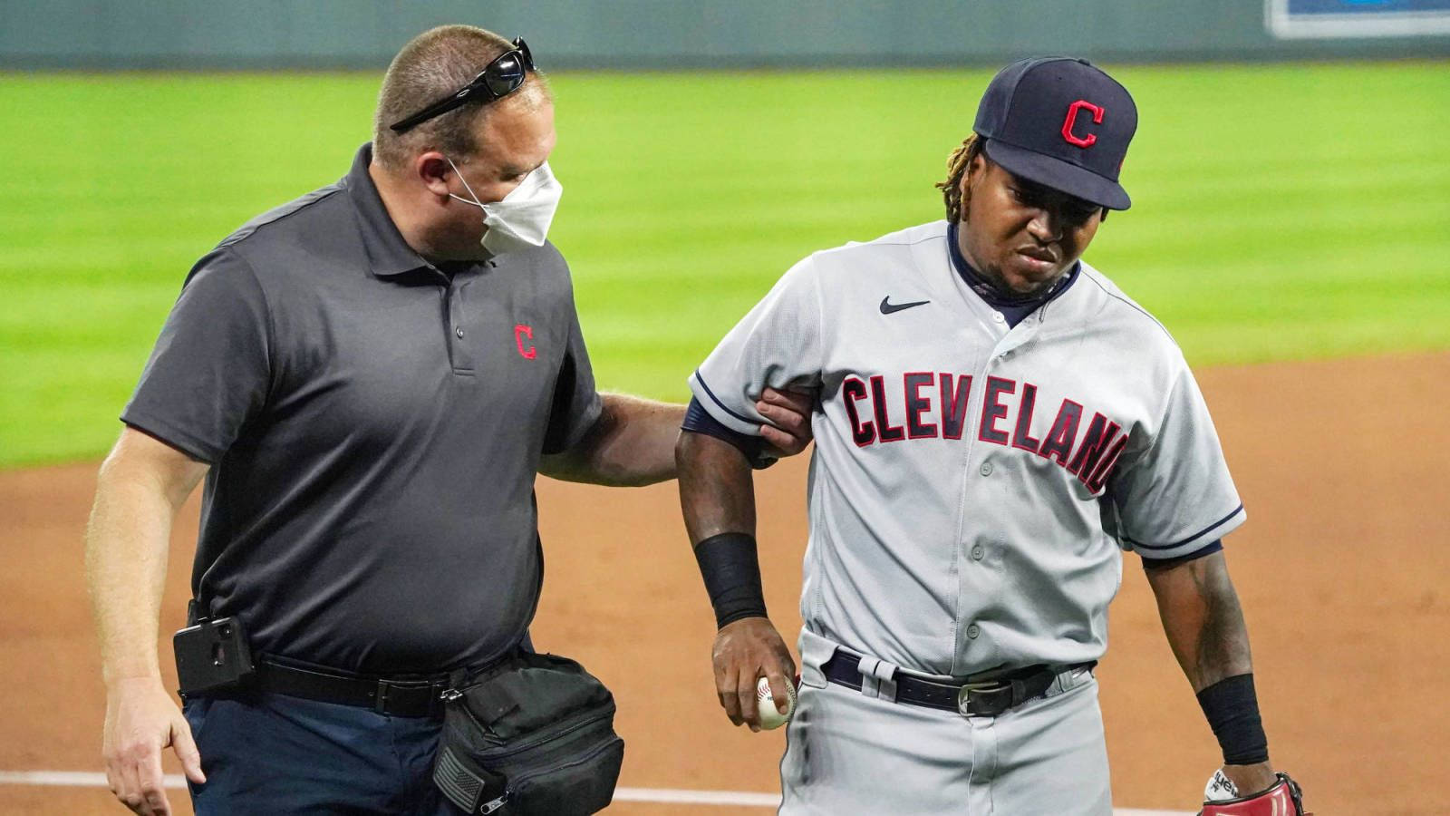 Jose Ramirez 桌布 壁紙 — 一名克里夫蘭棒球球員在球場燈光下由訓練員扶著手臂離開球場。