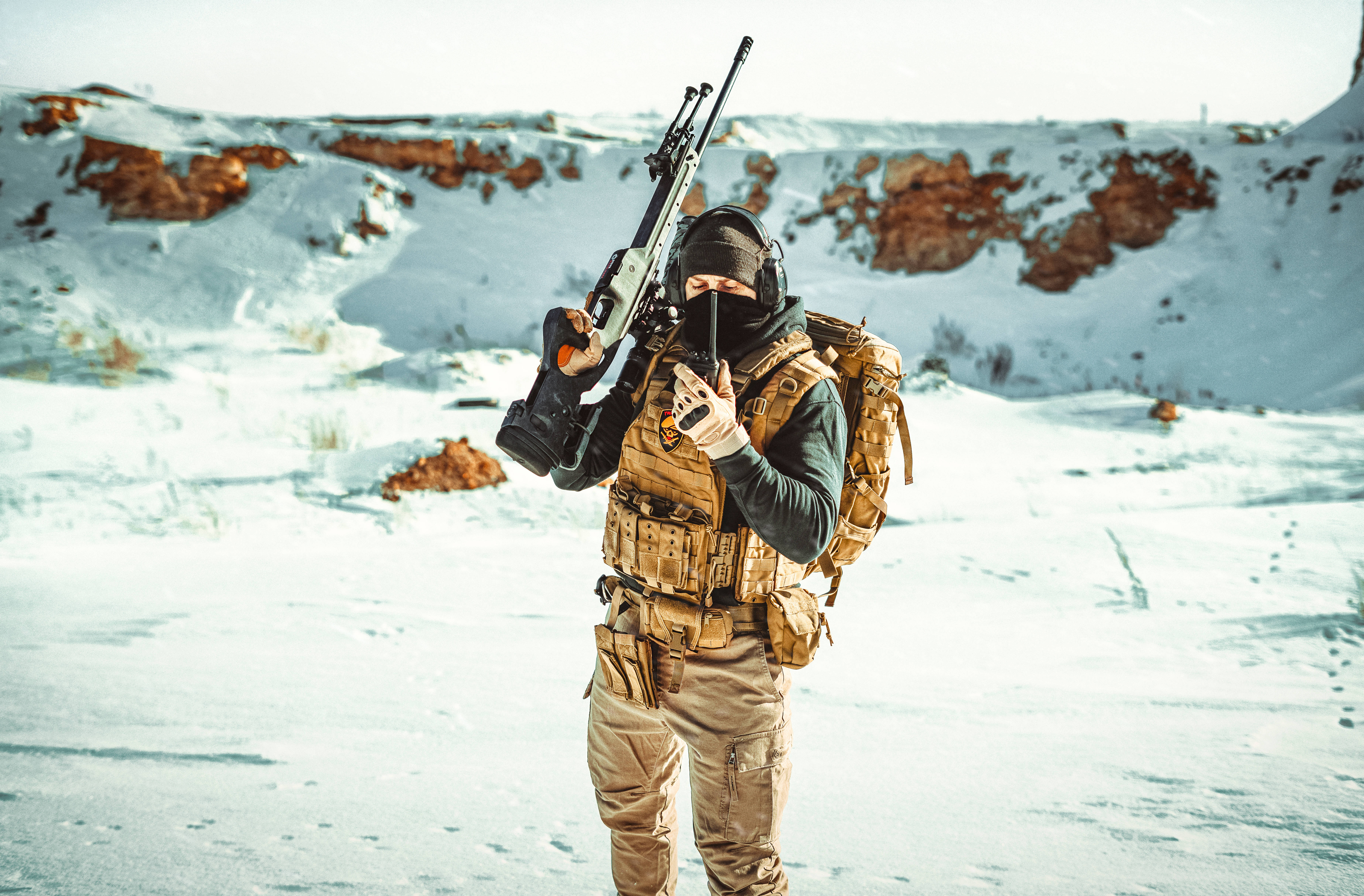 Kazakhstan 桌布 壁紙 — 一名全副武裝的士兵站在雪覆蓋的沙漠景觀中，手持步槍和無線電。