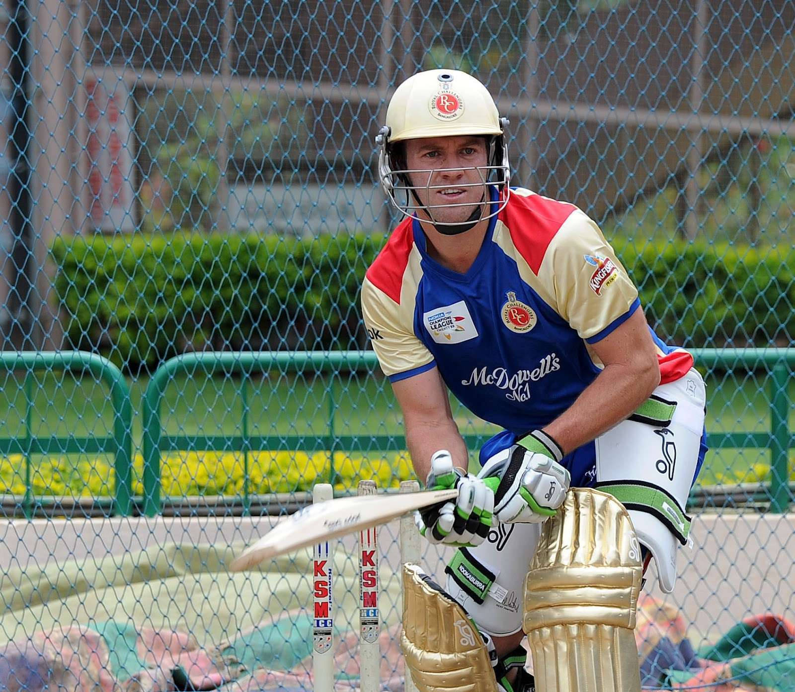 Ab De Villiers 桌布 壁紙 — 一名全副裝備的板球擊球手在鐵絲網後方的擊球區微笑著準備揮棒。