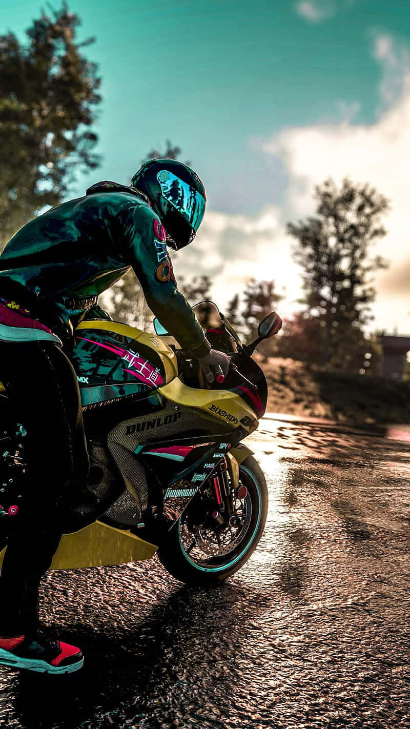Motorcycle iPhone 桌布 壁紙 — 一名全副裝備的機車騎士在戲劇性的日落天空下，在潮濕的柏油路上傾斜入彎。