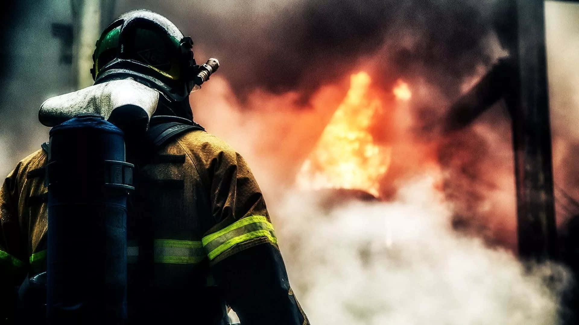 Fire Smoke 桌布 壁紙 — 一名全副裝備的消防員在猛烈火焰和濃煙中背光站立。