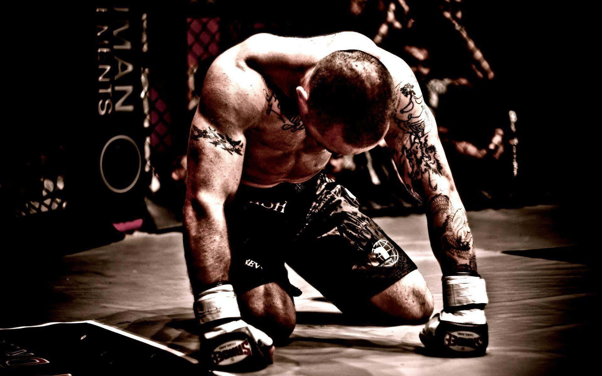 UFC 桌布 壁紙 — 一名刺青拳手在殘酷比賽後，於昏暗八角籠內的MMA墊上疲憊地跪著。