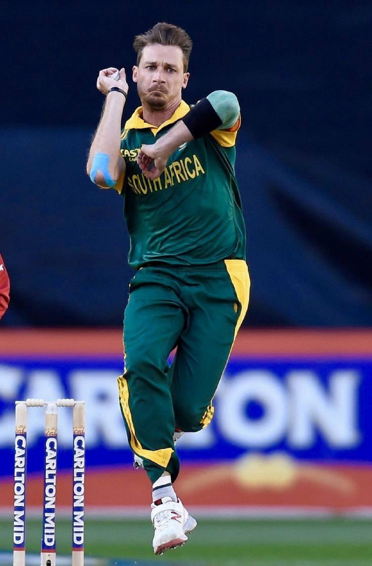 south africa cricket 桌布 壁紙 — 一名南非板球投手在球場背景下全神貫注地投球。
