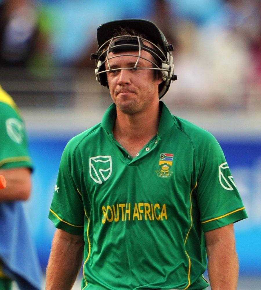 Ab De Villiers 桌布 壁紙 — 一名南非板球運動員身穿綠色制服和頭盔，在明亮的球場上專注地低頭注視。